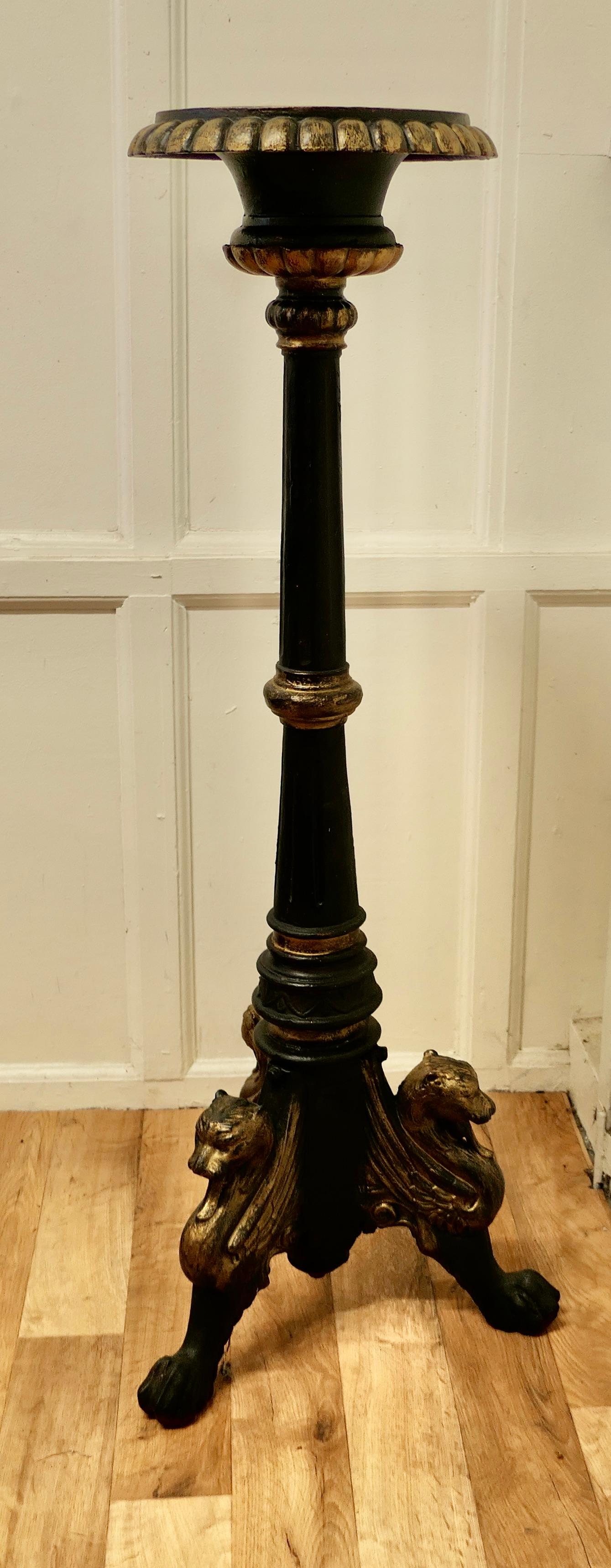 Tall Arts & Crafts cast iron candle stick or torchère.

This is a tall and very heavy Torchere, it has a pricket in the centre of the sconce and stands on a footed base which takes the form of 3 Lions 
The stand has a touch of gold on the black,