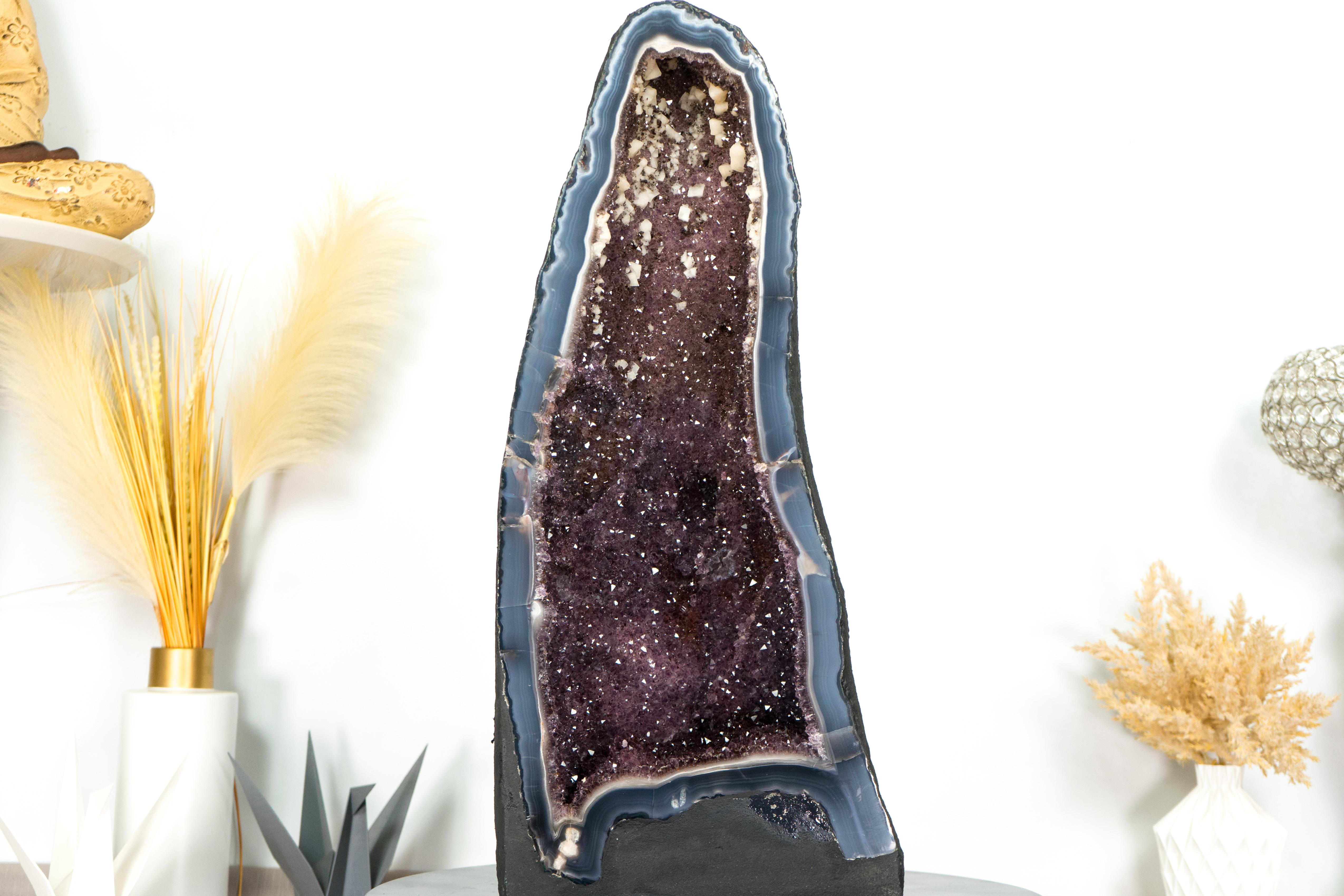 With spectacular blue banded agates, rare, beautiful aesthetics, added with spectacular shiny Amethyst that complements everything, this Agate with Amethyst Geode is a spectacular all-natural artwork that deserves a center space in your office,