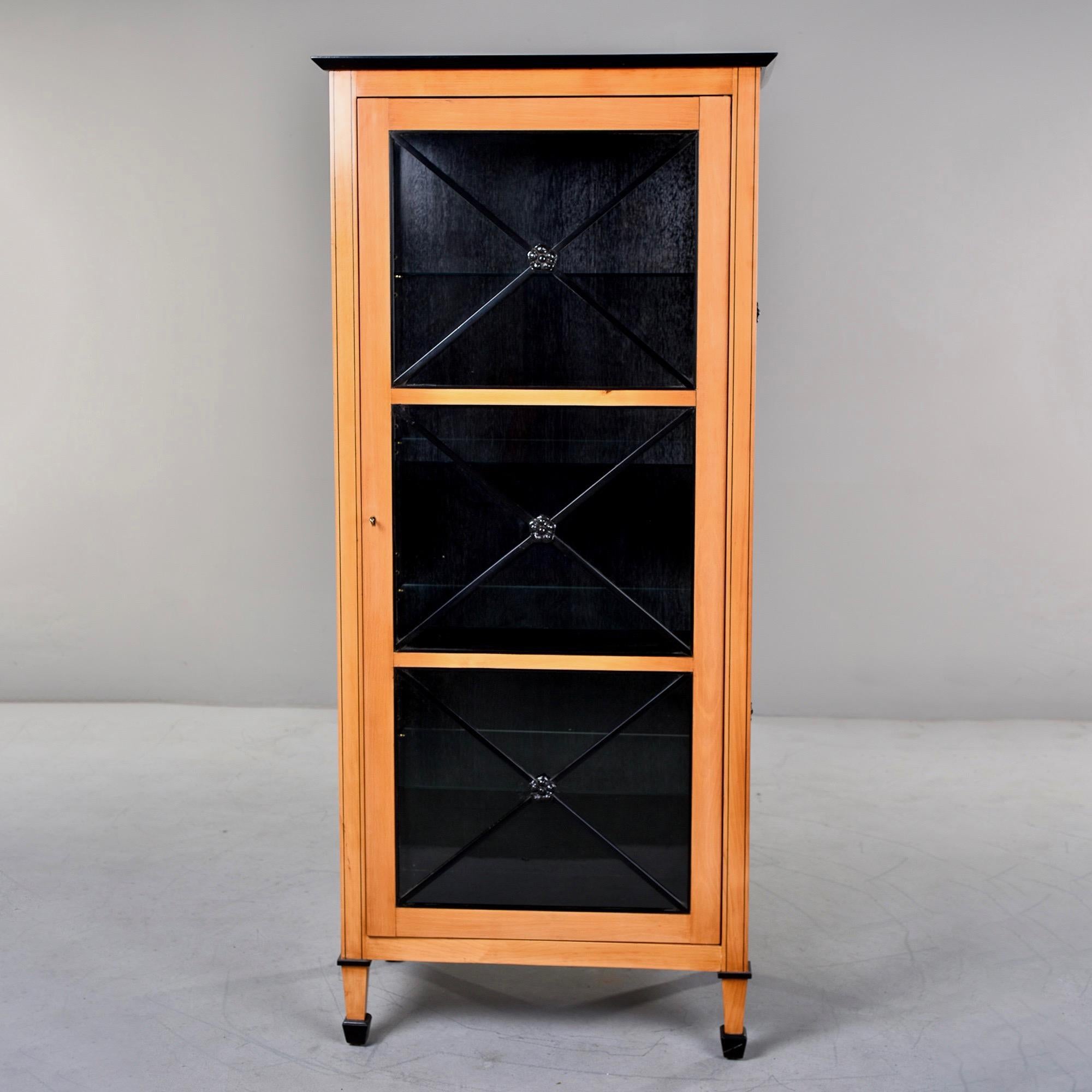 Tall Art Deco-inspired cabinet glass front door in maple with ebonised trim. Internal shelves, hand crafted to our specifications in England by custom cabinet makers. 32” wide and 19” deep including crown molding; body itself 30” wide and 18” deep.