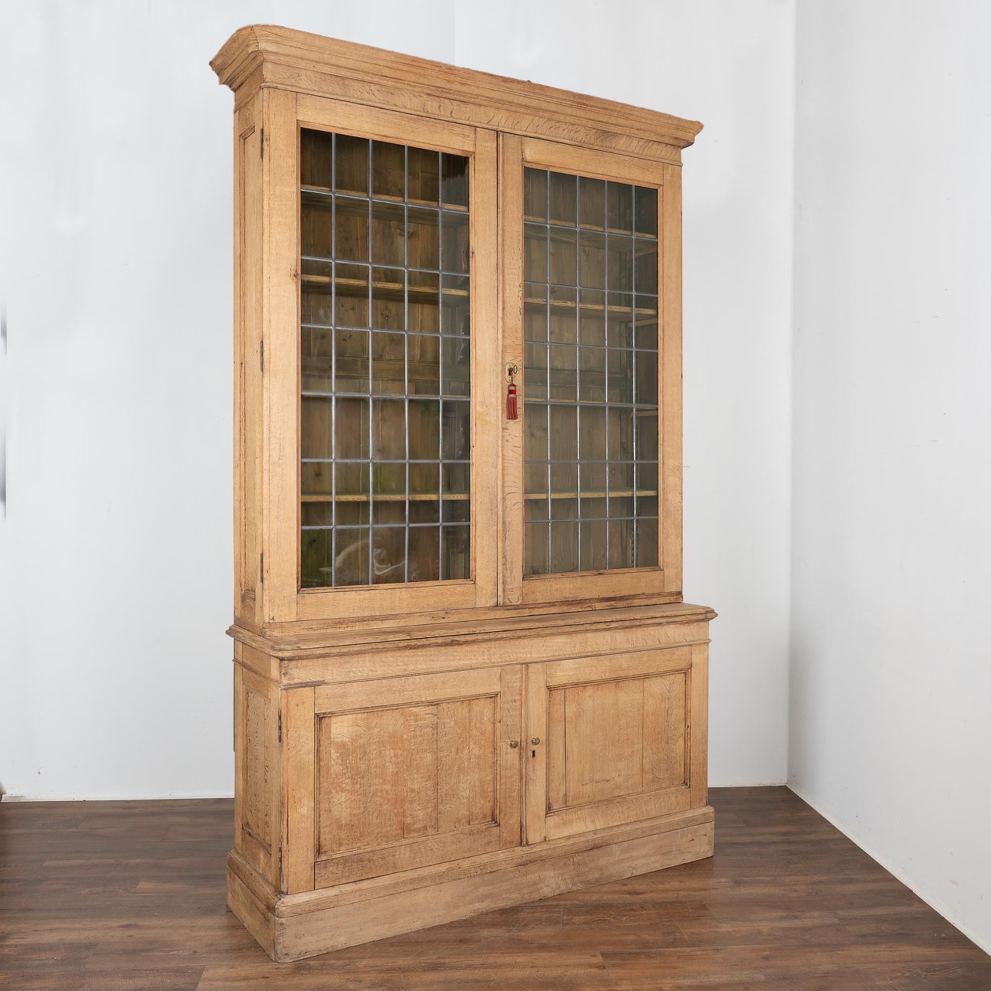 This large bleached oak bookcase is statuesque in size and detail. At 9.5' tall, the lead panes of the large glass doors add to its strong visual presence.
Originally the 