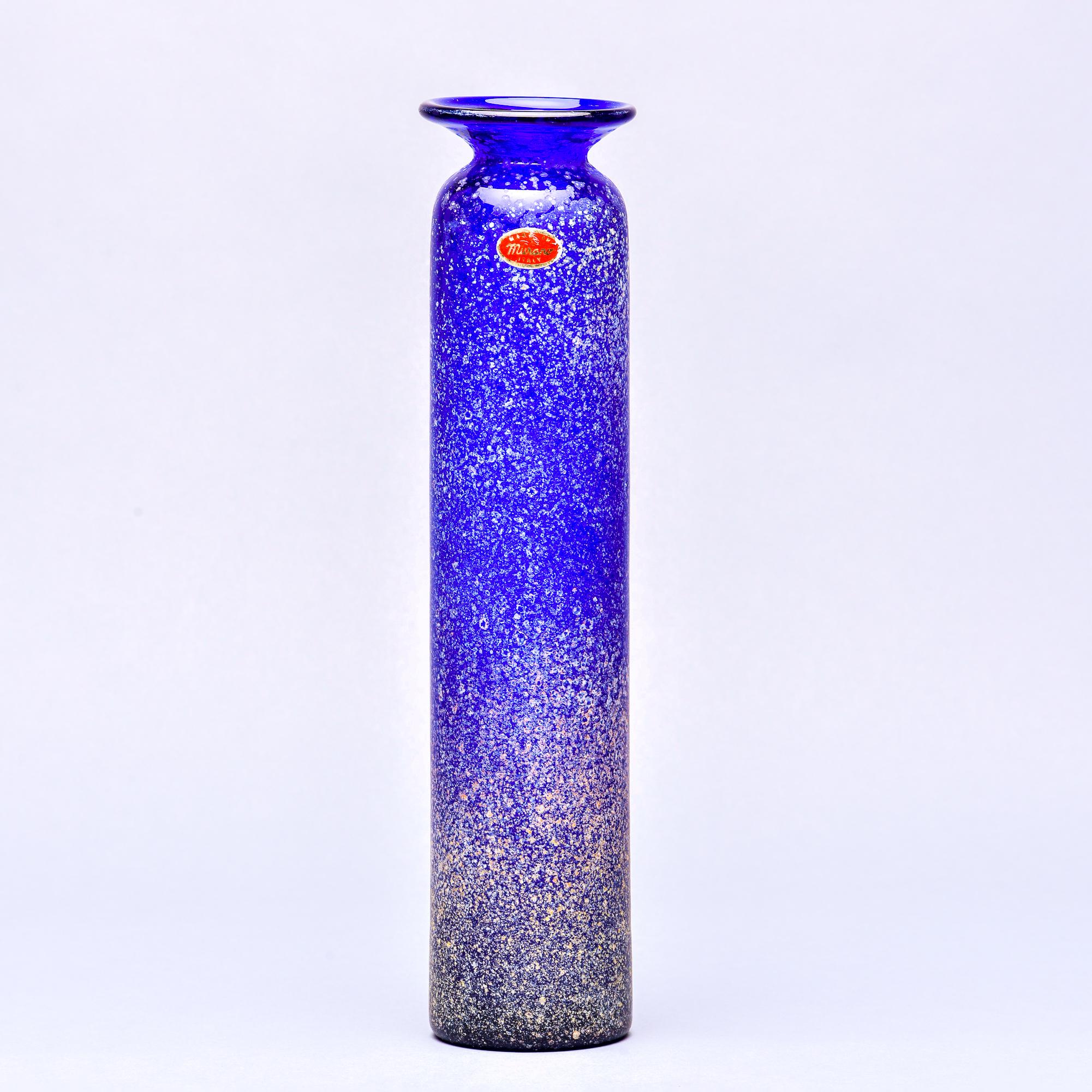 Found in Italy, this circa 1960s tall slender scavo style Murano glass vase in cobalt blue stands just under 15” tall. Original foil Murano label still affixed but vase is unsigned by maker. Very good vintage condition with no flaws found and only