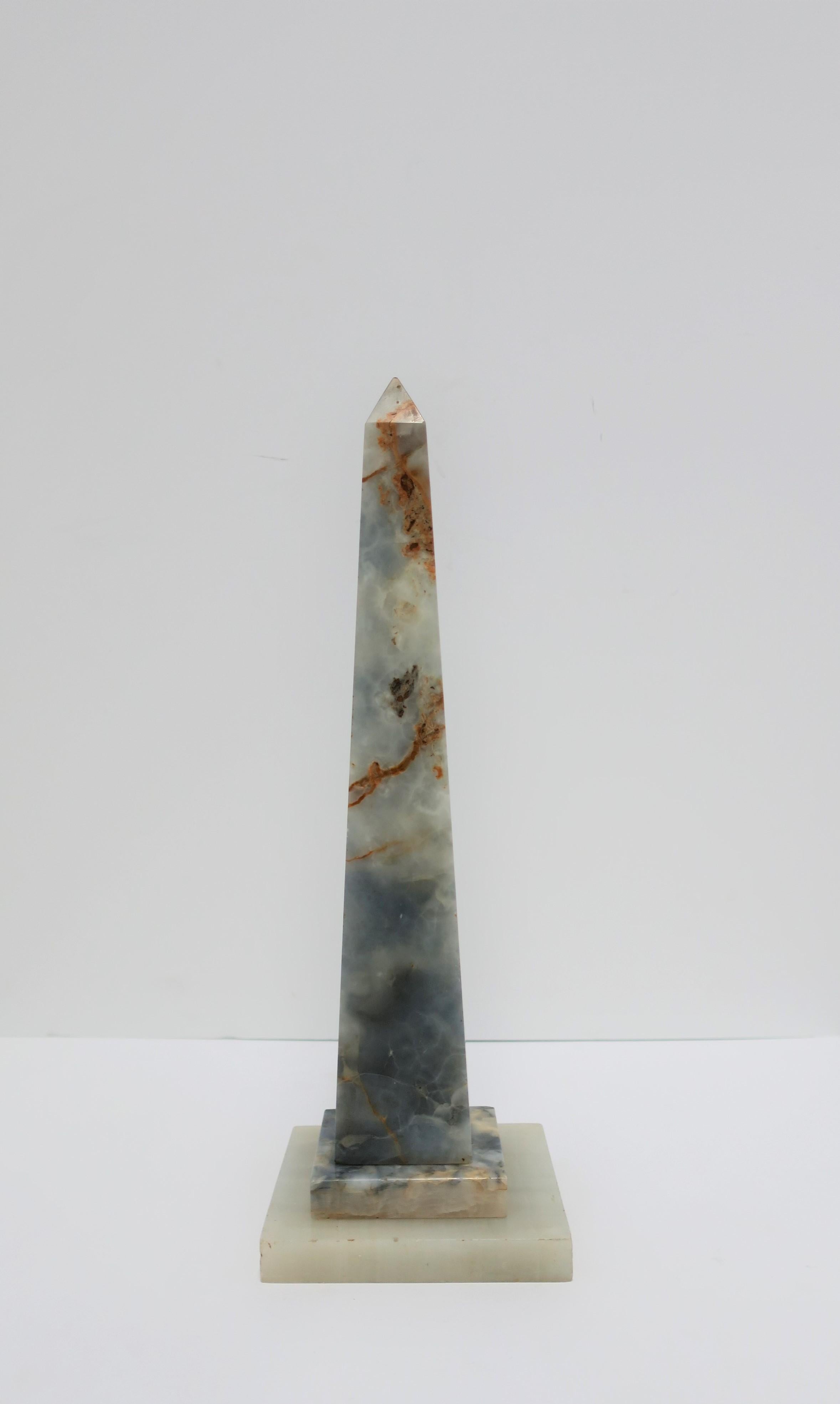 A relatively tall onyx obelisk sculpture piece in blue, light blue, white, and brown hues, in the style of Modern, circa mid-20th century or earlier, Italy. 

Piece measures: 15.25