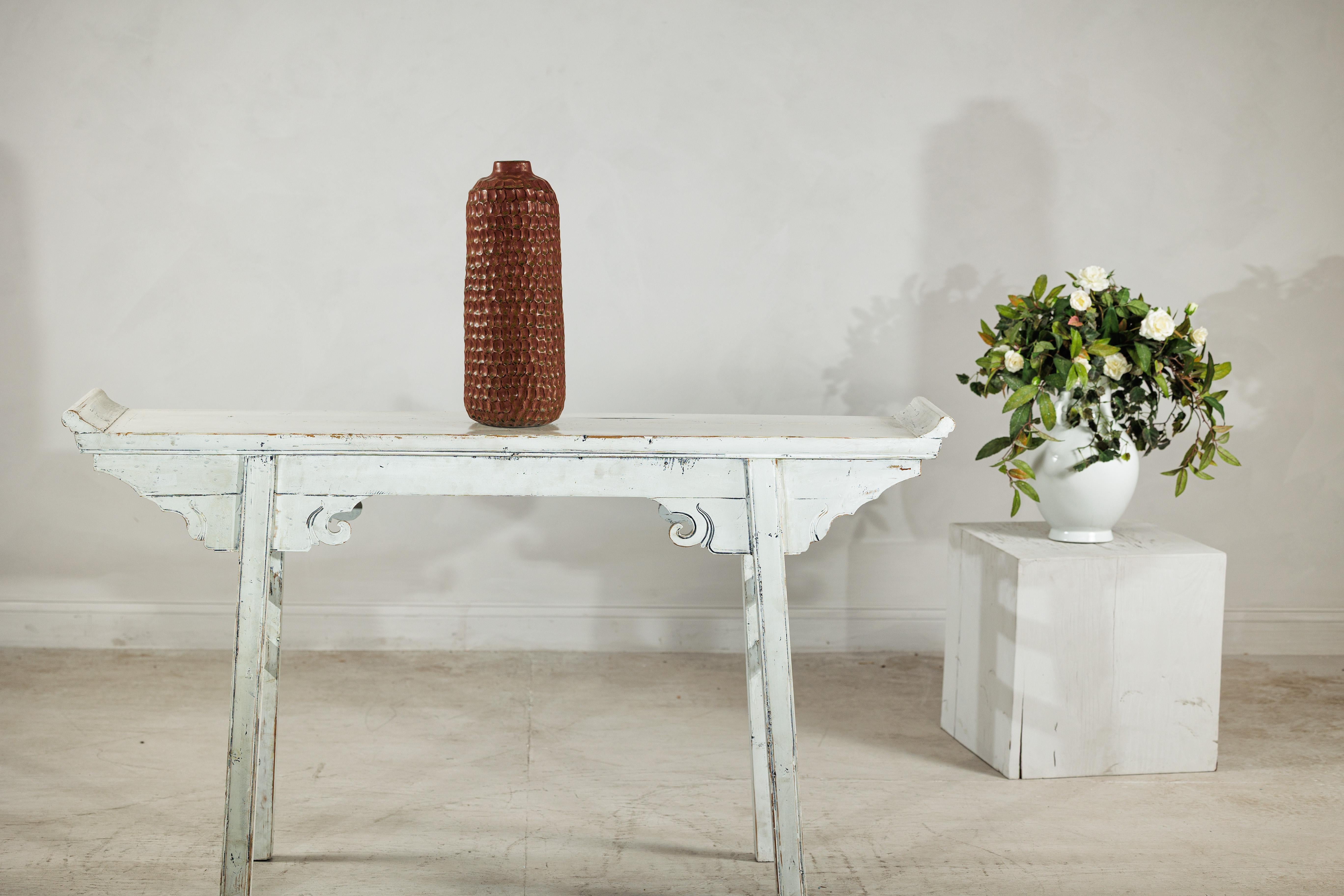 Ricco di texture e splendidamente realizzato, questo vaso alto in ceramica marrone presenta una superficie a nido d'ape che conferisce profondità e dimensione alla sua forma cilindrica. Lo smalto combina i toni del marrone terroso con morbide