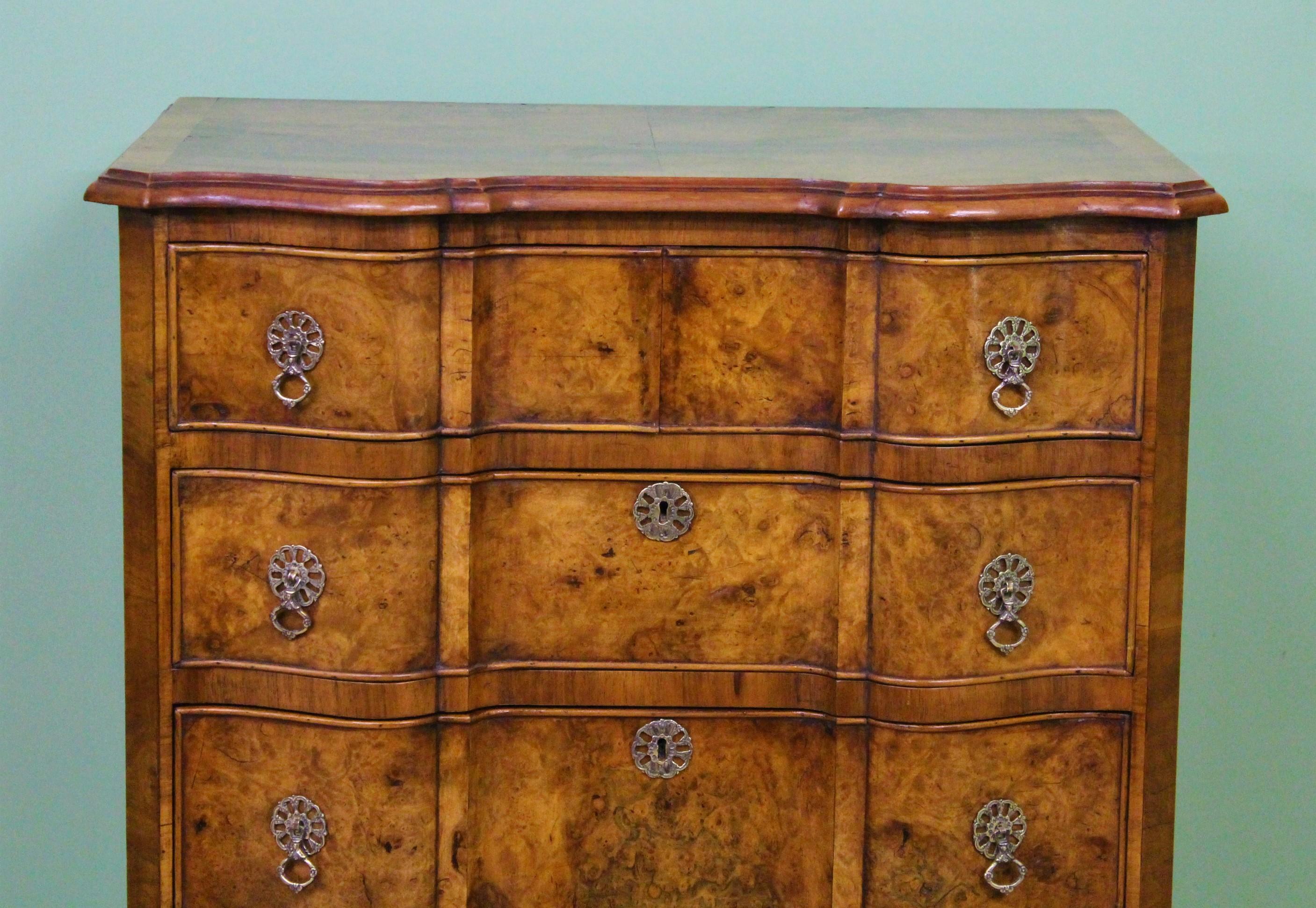 An attractive and practical tall burr walnut chest of drawers. Of serpentine fronted form and in the Queen Anne style. Well made in solid walnut and attractive burr walnut veneers onto a solid oak carcas. With an arrangement of 2 short over 5 long,