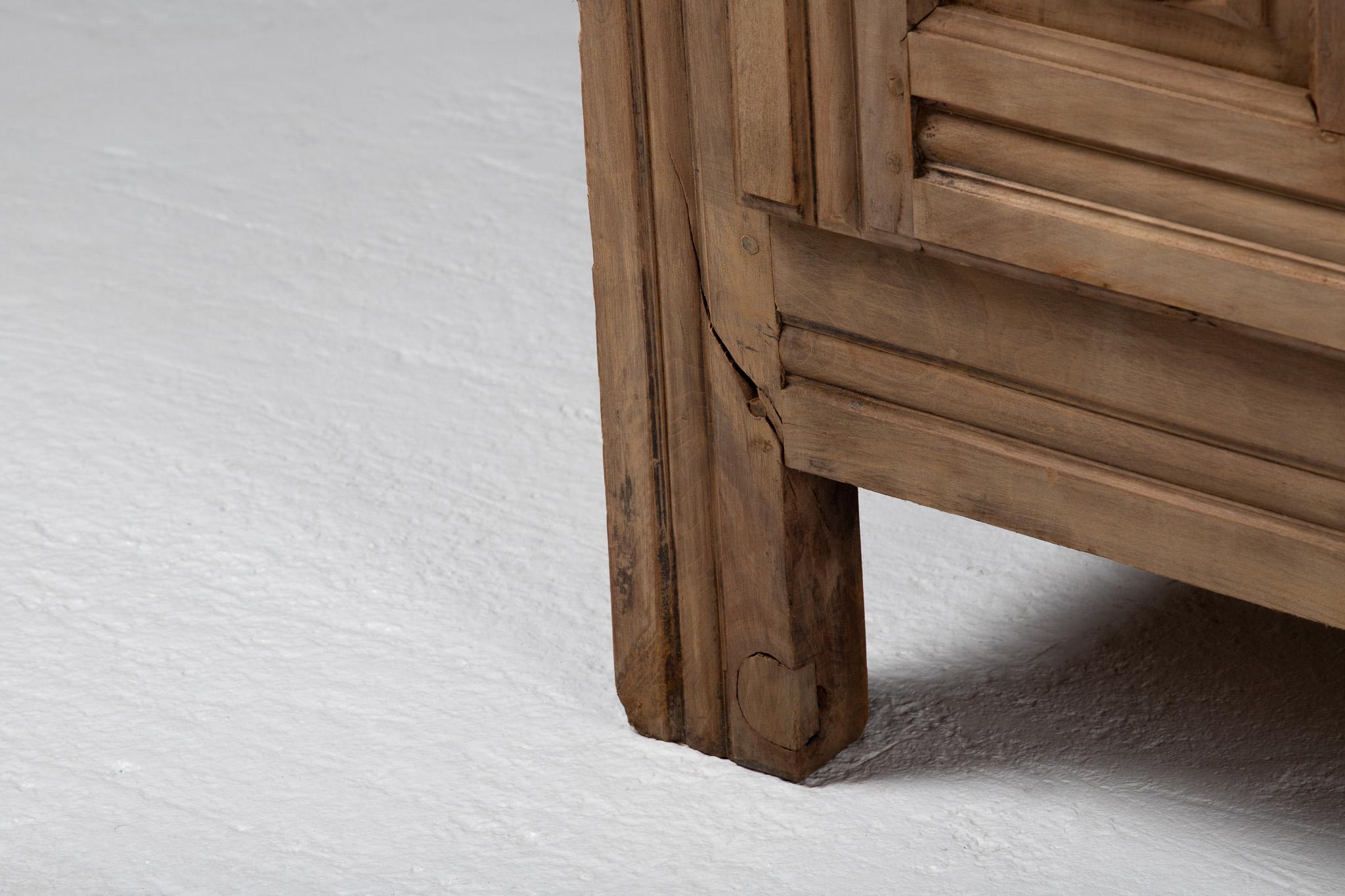 Monolithic in stance yet intricate in surface, this tall French cabinet reveals a façade of concentric rosettes and squared panels, arranged with the solemn rhythm of a liturgical object. The carving is architectural in spirit—recessed, symmetrical,