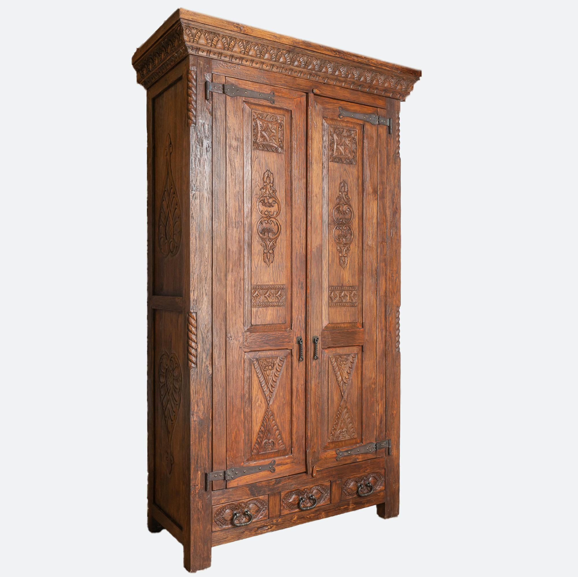 At almost 10' tall, this dark oak armoire makes a dramatic statement while providing great storage in the spacious interior with three shelves.
The beautiful carved details are accented with iron studs, pulls and heavy hinges all add to the