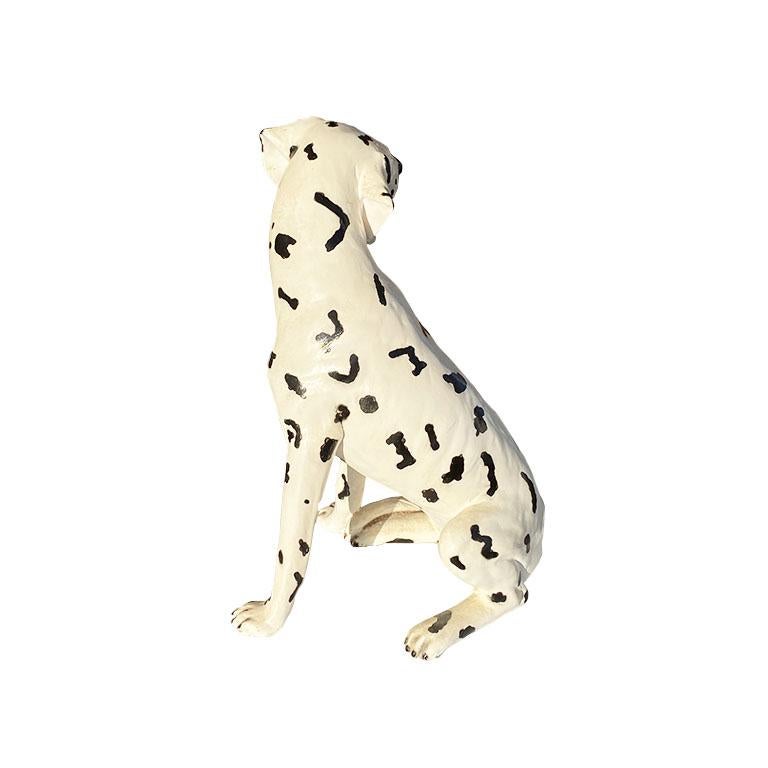 A gorgeous classic Dalmatian dog statue in black and white. This beautiful hand-painted canine is created from ceramic, and hand-painted in black and white. He sits on his loins and has floppy spotted ears. He has piercing yellow eyes created from