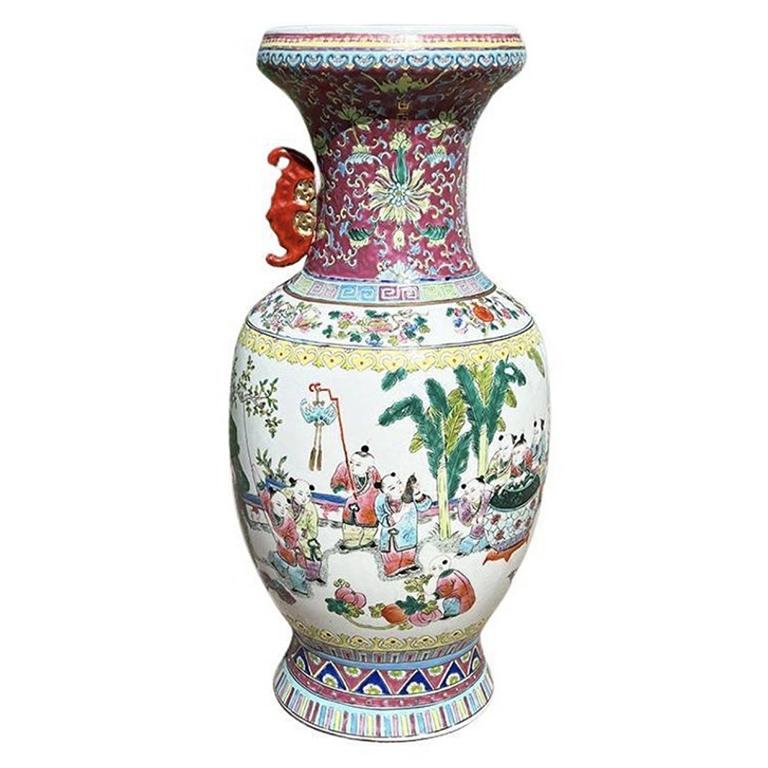 A tall chinoiserie famille rose ceramic vase. This piece is very tall and could be used as a floor vase, or to decorate a credenza or dining table. The top of the vessel is hand-painted in a mauve pink with flowers in blue, yellow, and different