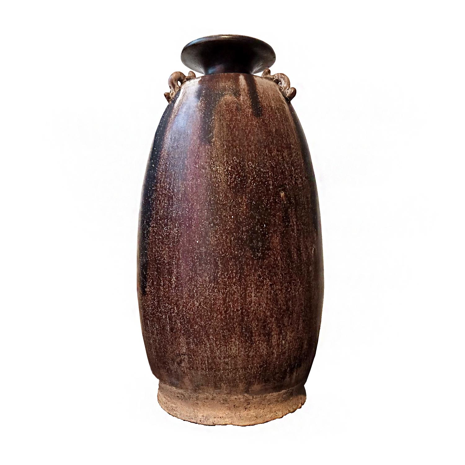 A tall brown ceramic vase / urn with brown glaze, with small loop handles on its neck. Hand-crafted in Thailand, in the tradition of antique Thai earthenware. With its mottled brown glaze, this piece makes for a unique decorative piece in most