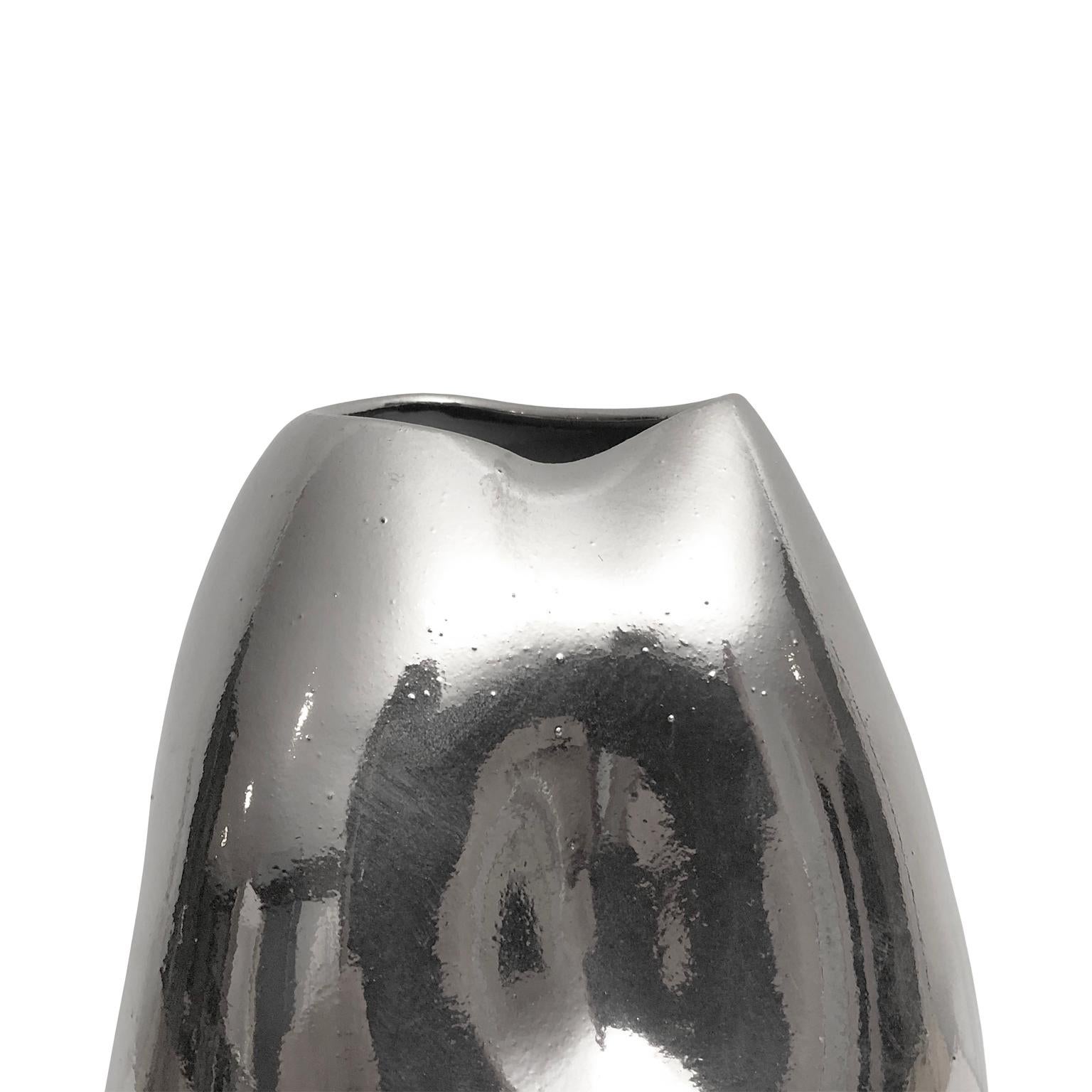 Tall ceramic triple dent vase with polished white gold lustre glaze by Sandi Fellman, 2019. 

Veteran photographer Sandi Fellman's ceramic vessels are an exploration of a new medium. The forms, palettes, and sensuality of her photos can be found