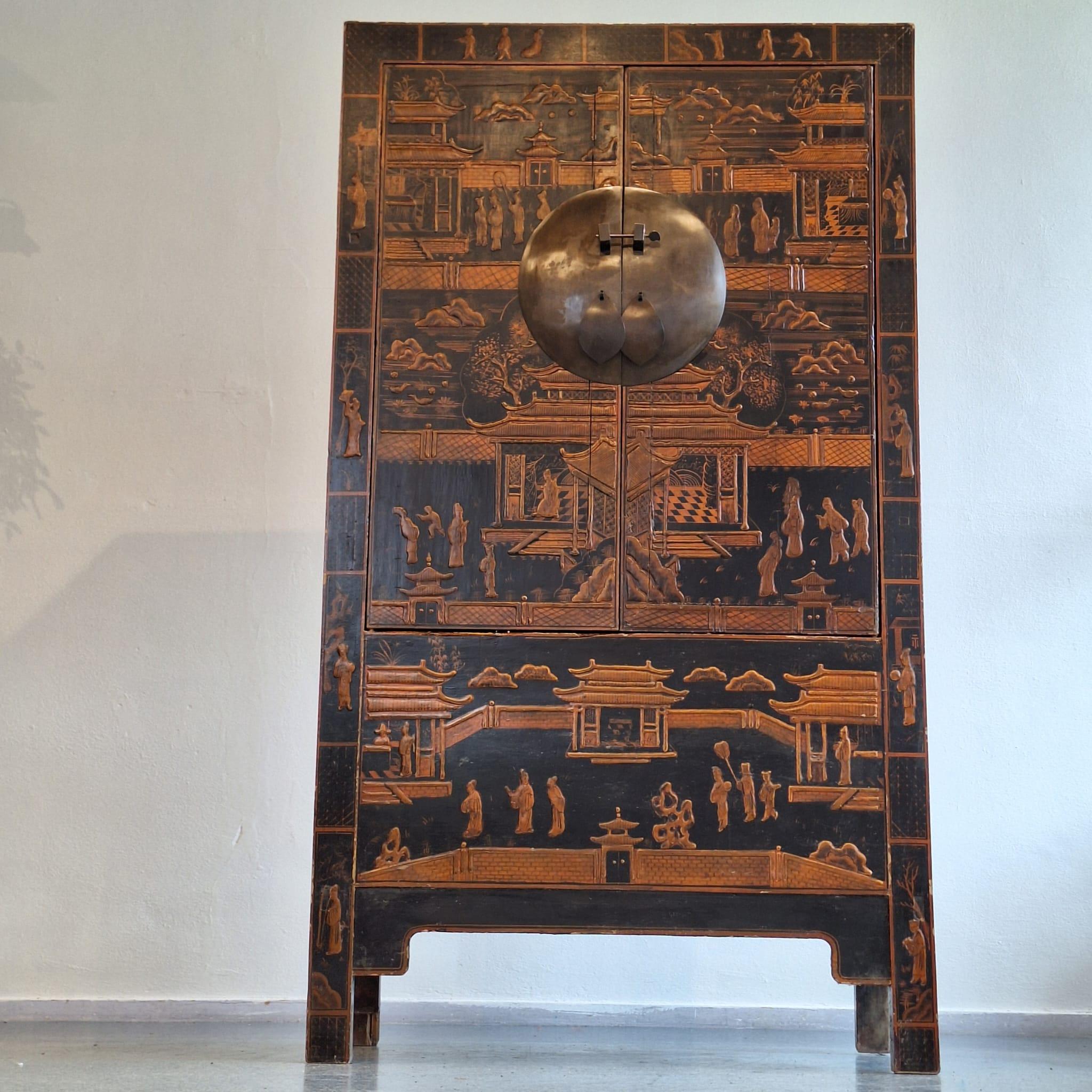 Questo mobile da sposa cinese alto e antico è un pezzo d'arredamento impressionante che trasuda la ricca cultura cinese. Le immagini color arancio terra su uno sfondo nero laccato lo rendono un vero e proprio richiamo visivo. Le decorazioni,