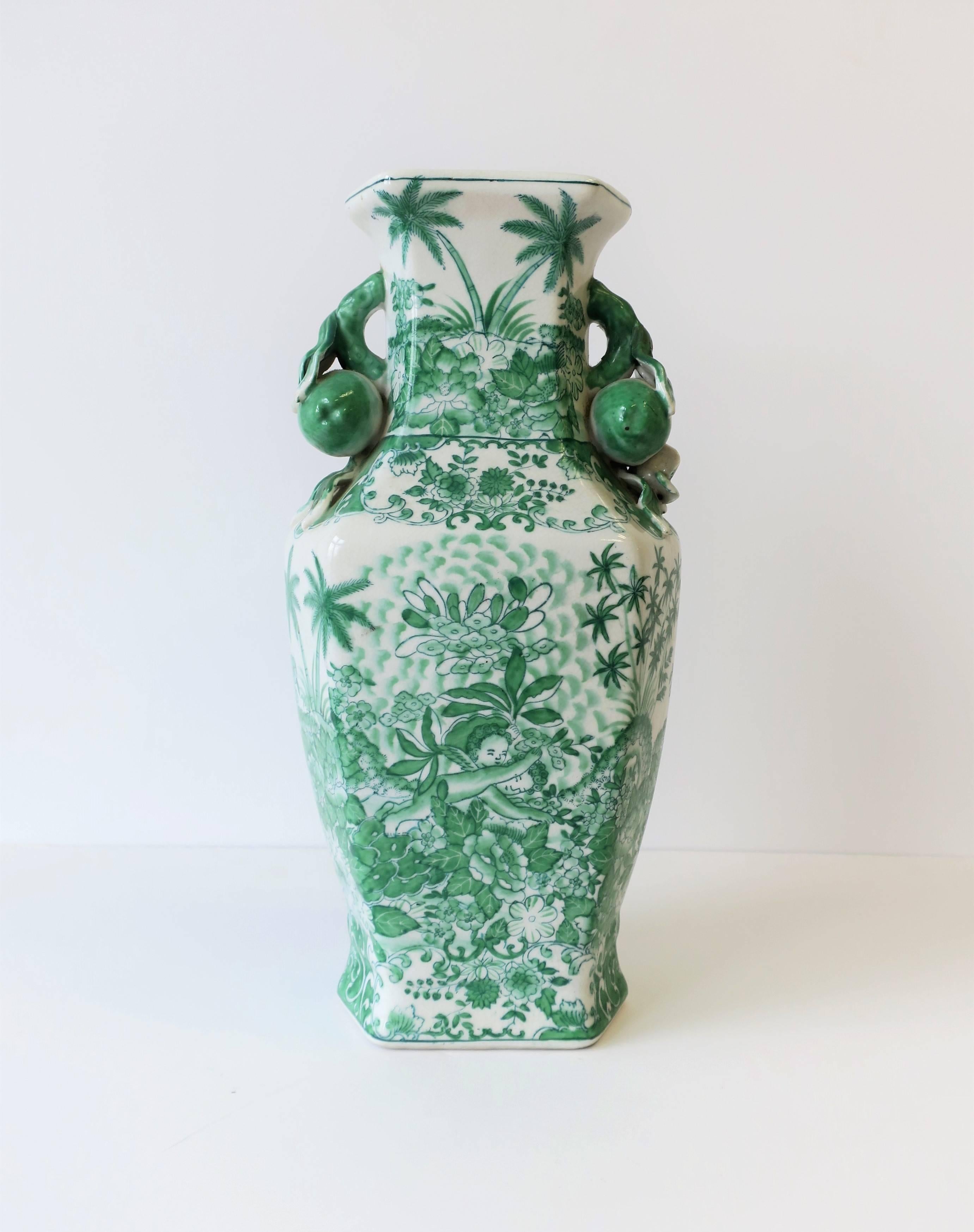 A beautiful, relatively tall, green and white ceramic vase, circa late 20th century, Republic of China. Vase, with a hexagon shape, has fruit, floral and leaf design at neck, complimenting it's overall design of palm trees, leaves, and flowers.