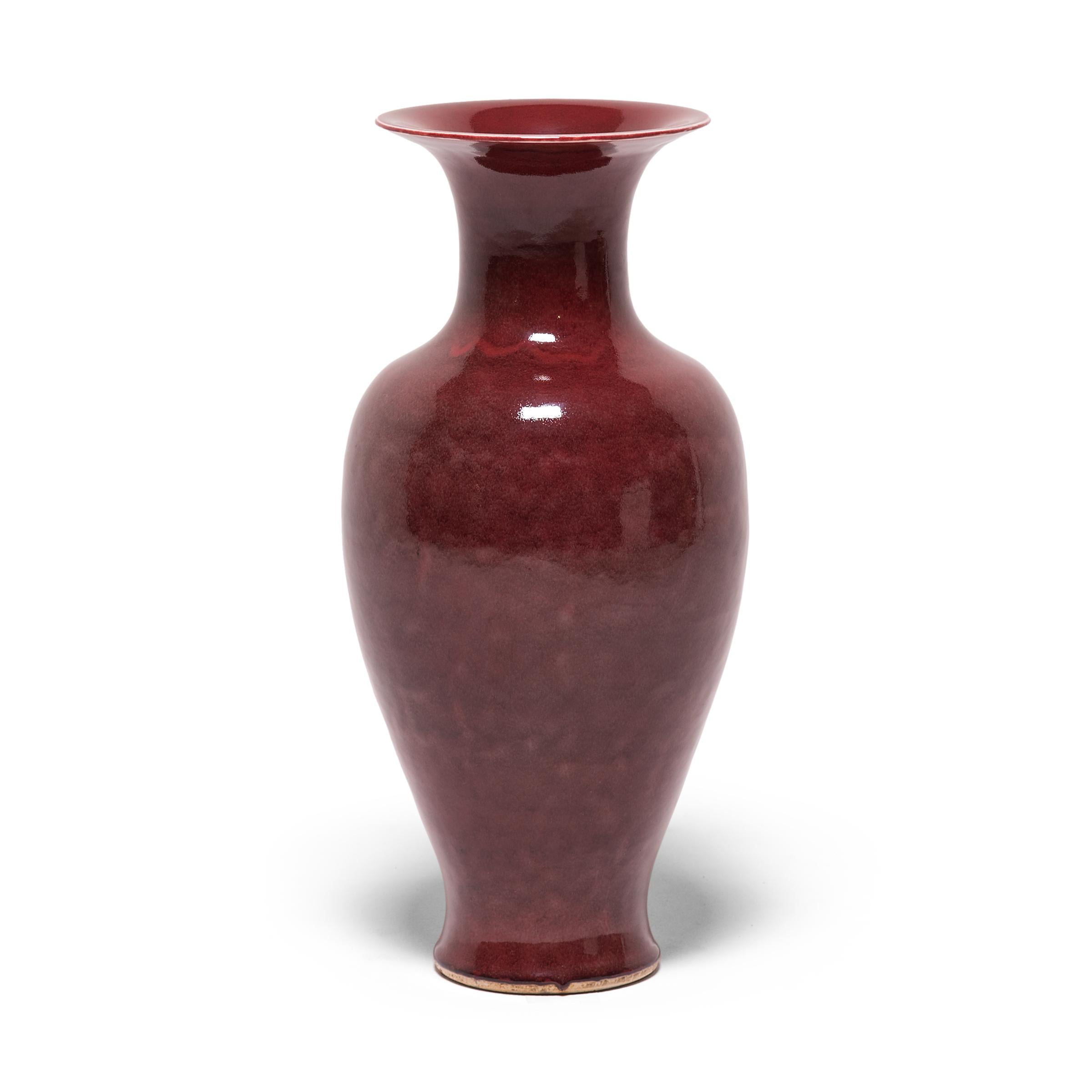 A reactive oxblood glaze coats this traditional fantail-shaped vase in eye-catching swirls of rich red. Compared to the color of crushed strawberries, red wine, or dried blood, the glaze contains large amounts of copper, which can be unpredictable