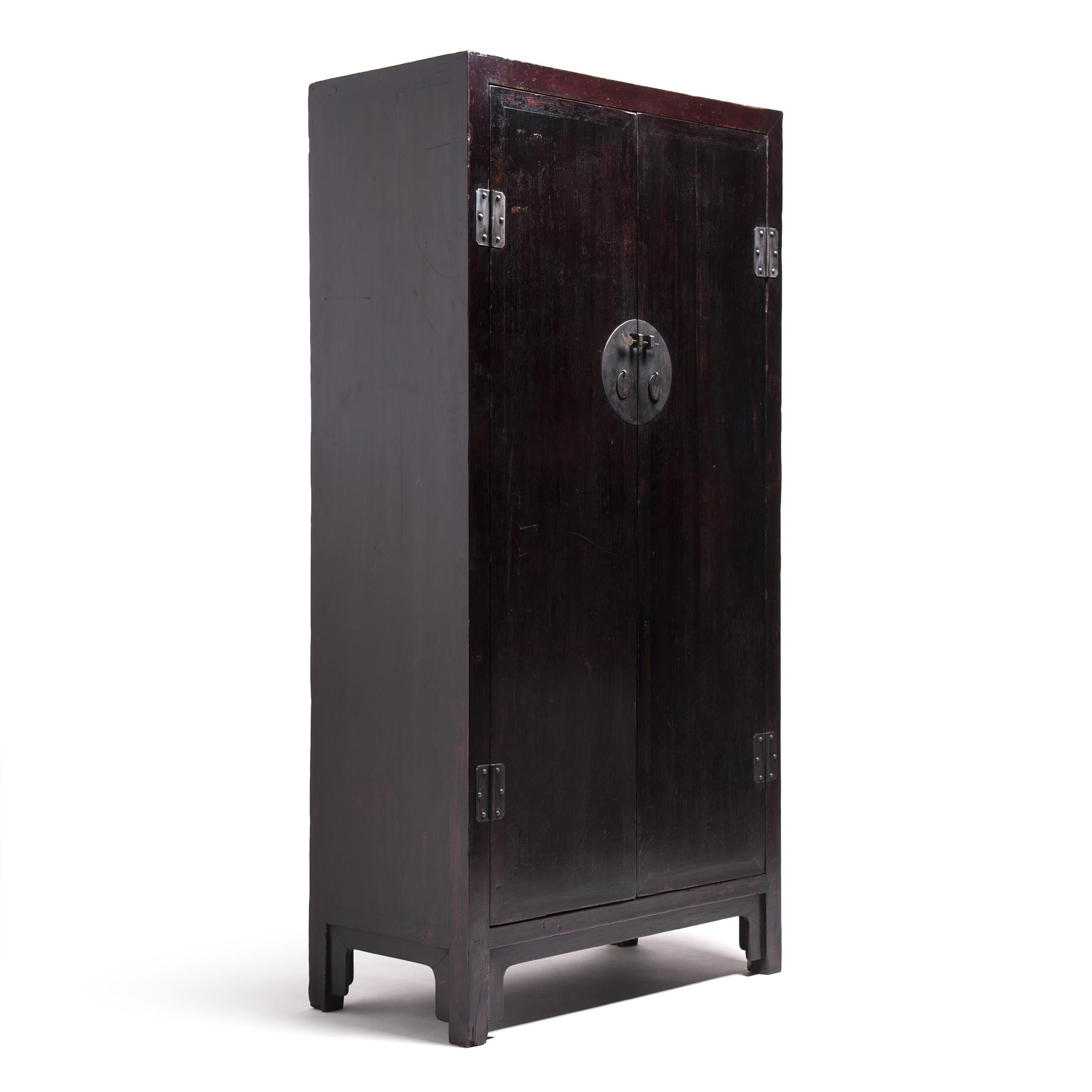 Unusual riveted hinge plates and a full-moon sliding door latch made of solid brass lend texture and metallic contrast to this simply styled, tall elm cabinet. In its exacting proportions, and masterful mortise-and-tenon construction, this