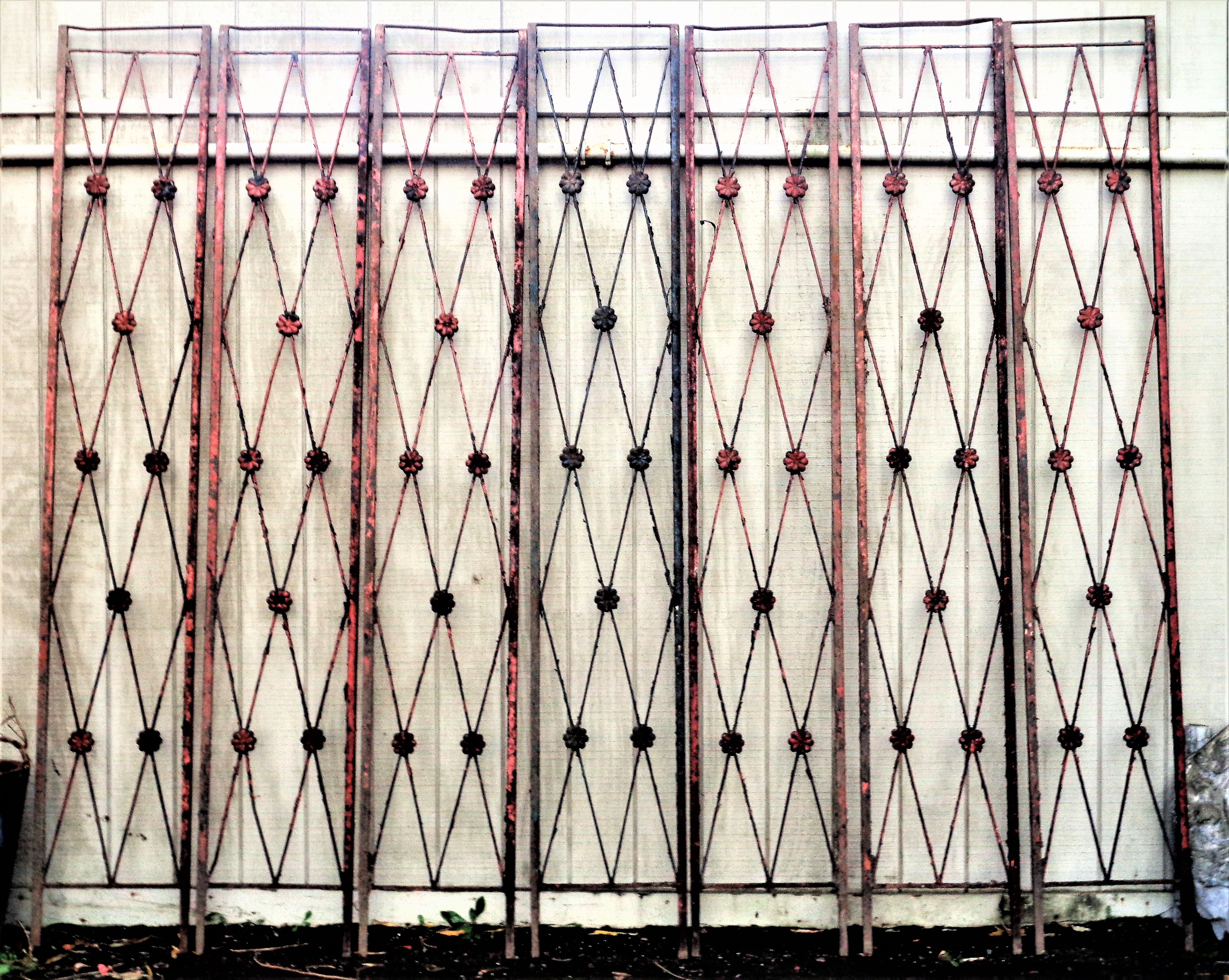 Eine Gruppe von sieben architektonischen Eisenpaneelen im klassischen Directoire-Stil mit abblätternder Oberfläche
schwarze Farbe über der lachsrot lackierten Originaloberfläche. Massives Eisen mit gekreuztem X und erhabenen, detaillierten Rosetten