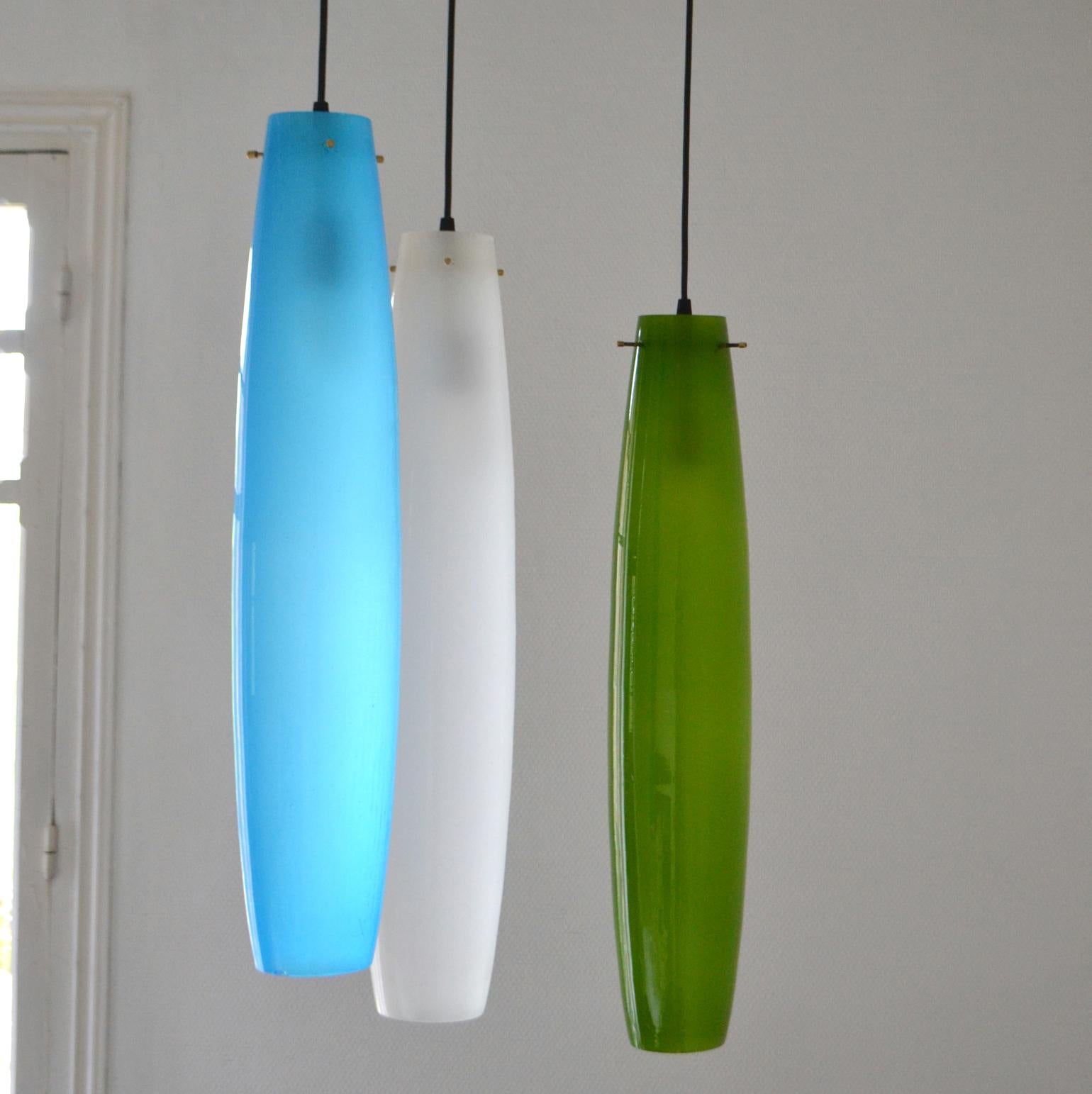 Two sets of 3 colored large elongated Murano blown glass pendants in blue, green (Inside is a blown thin inner layer of white opal translucent glass to spread a warm and soft light) and white. The ellipse shaped ceiling pendants are suspended by