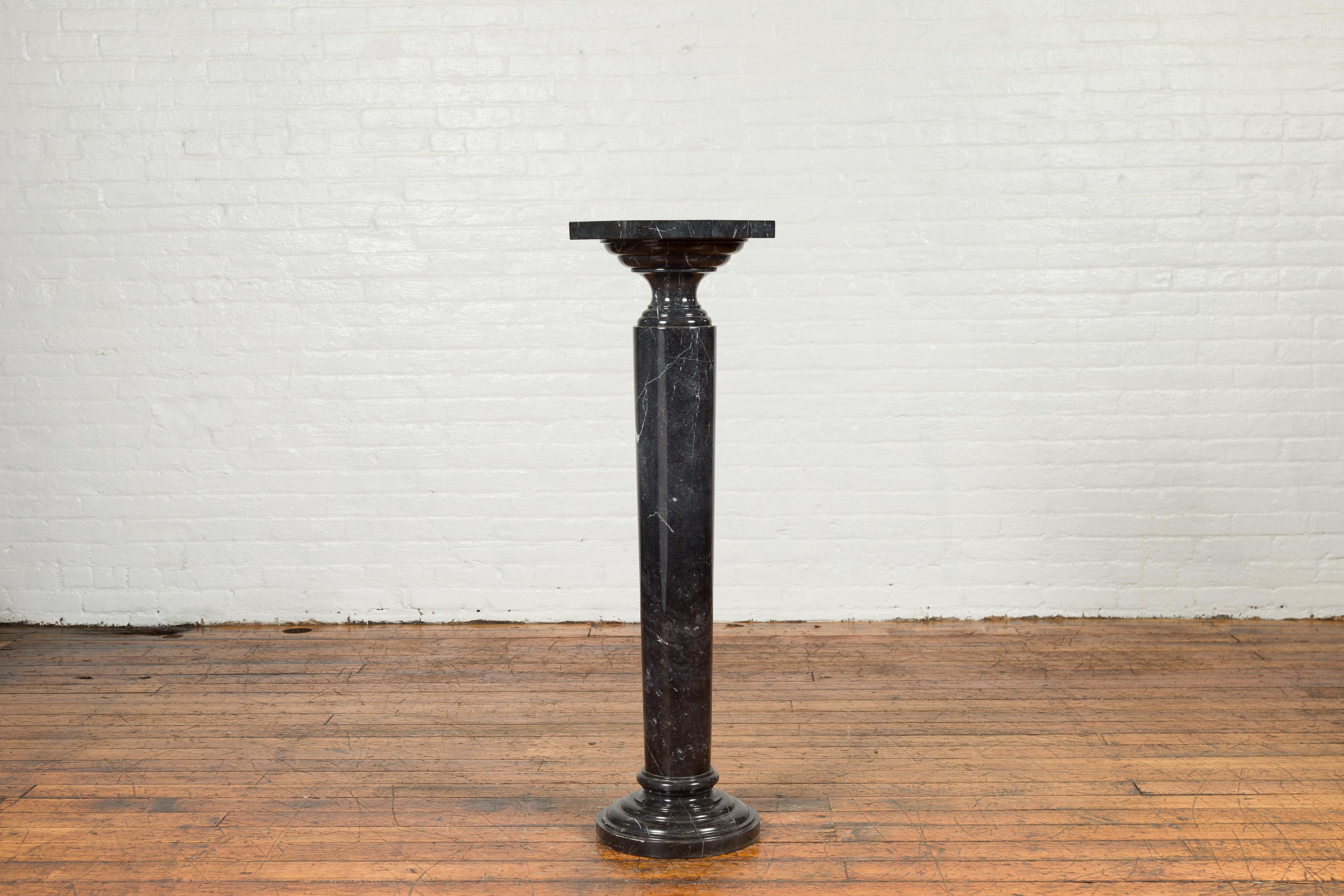 A tall contemporary Indian black Carrara marble pedestal with octagonal top and column base. Crafted in India, this tall pedestal draws our attention with its black veined Carrara marble and pure lines. Featuring an octagonal top, the pedestal