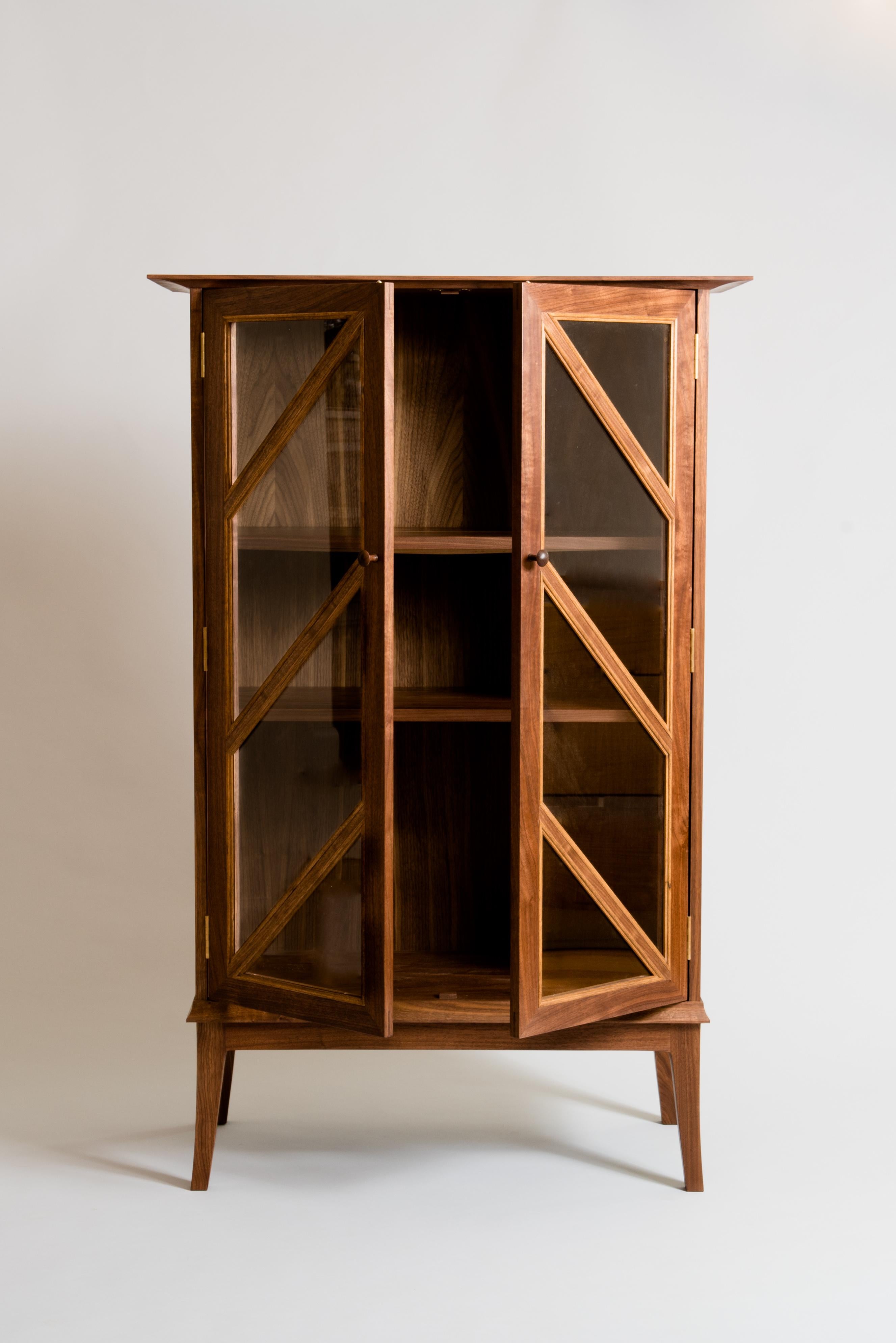 This cabinet is a clean, contemporary piece with traditional elements including a molding pattern unique to Meredith Hart Furniture over the glass doors. Originally designed to hold a wine collection, it could function as anything from a bookcase to
