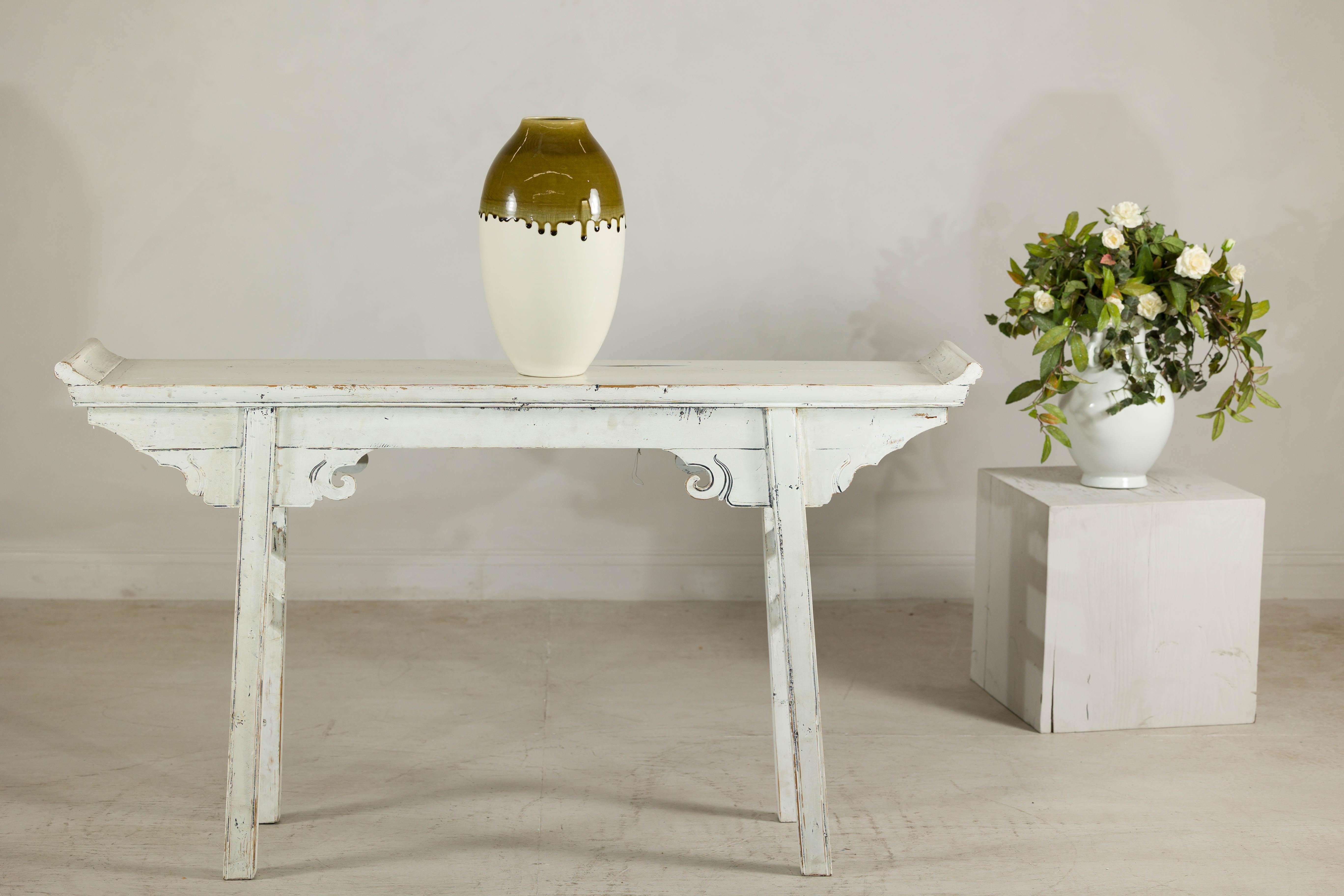 With its evocative glaze and graceful silhouette, this tall artisan vase brings a painterly touch to ceramic form. The surface is divided into two harmonious zones: a creamy, matte lower body that feels soft to the eye, and a richly toned olive