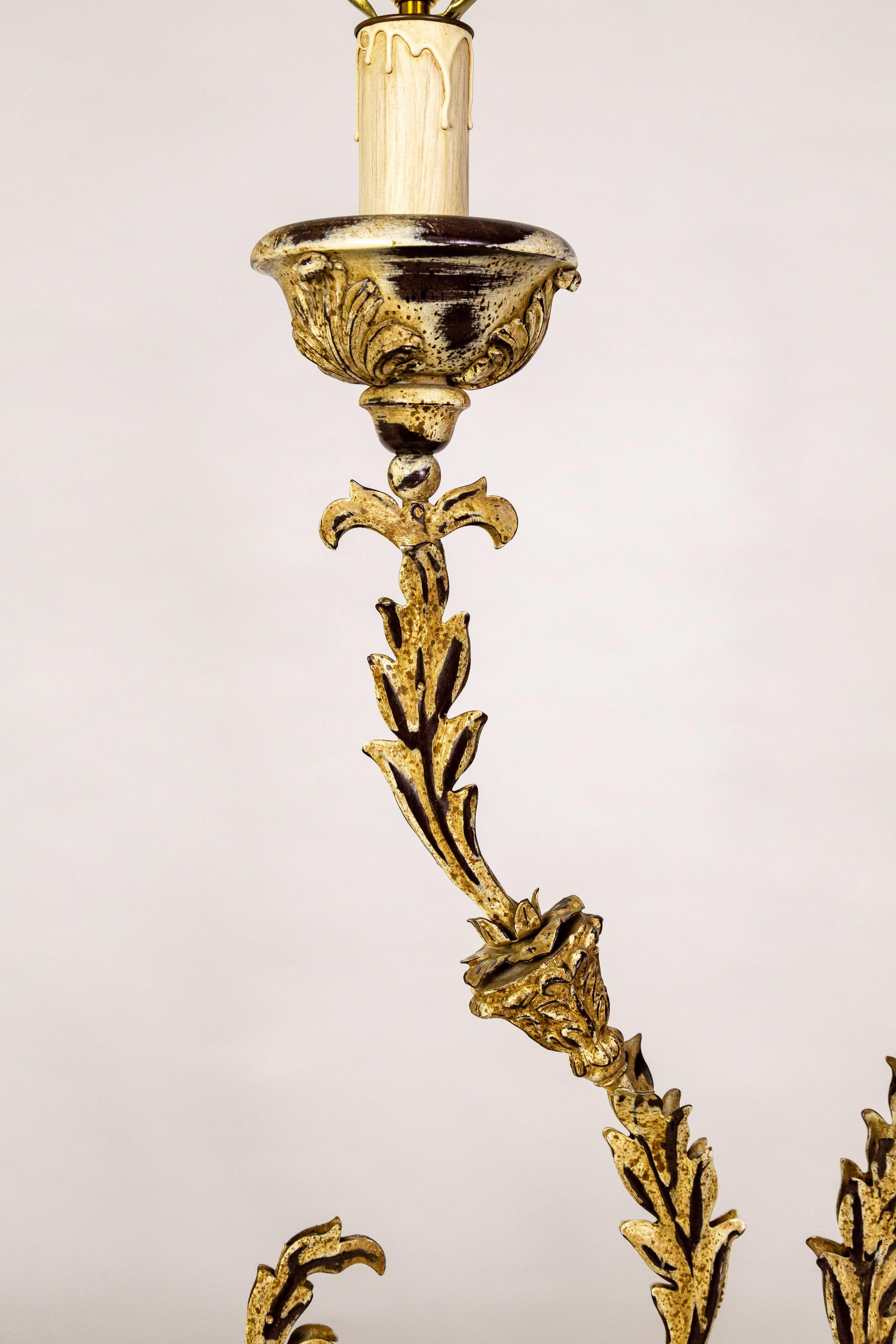 A pair of tole lamps with a unique curved shape. They are slender acanthus leaves with a bloom in the middle mounted on a turned form with a hexagon base. The painted finish is golden beige accented with dark brown. They have candlestick-style