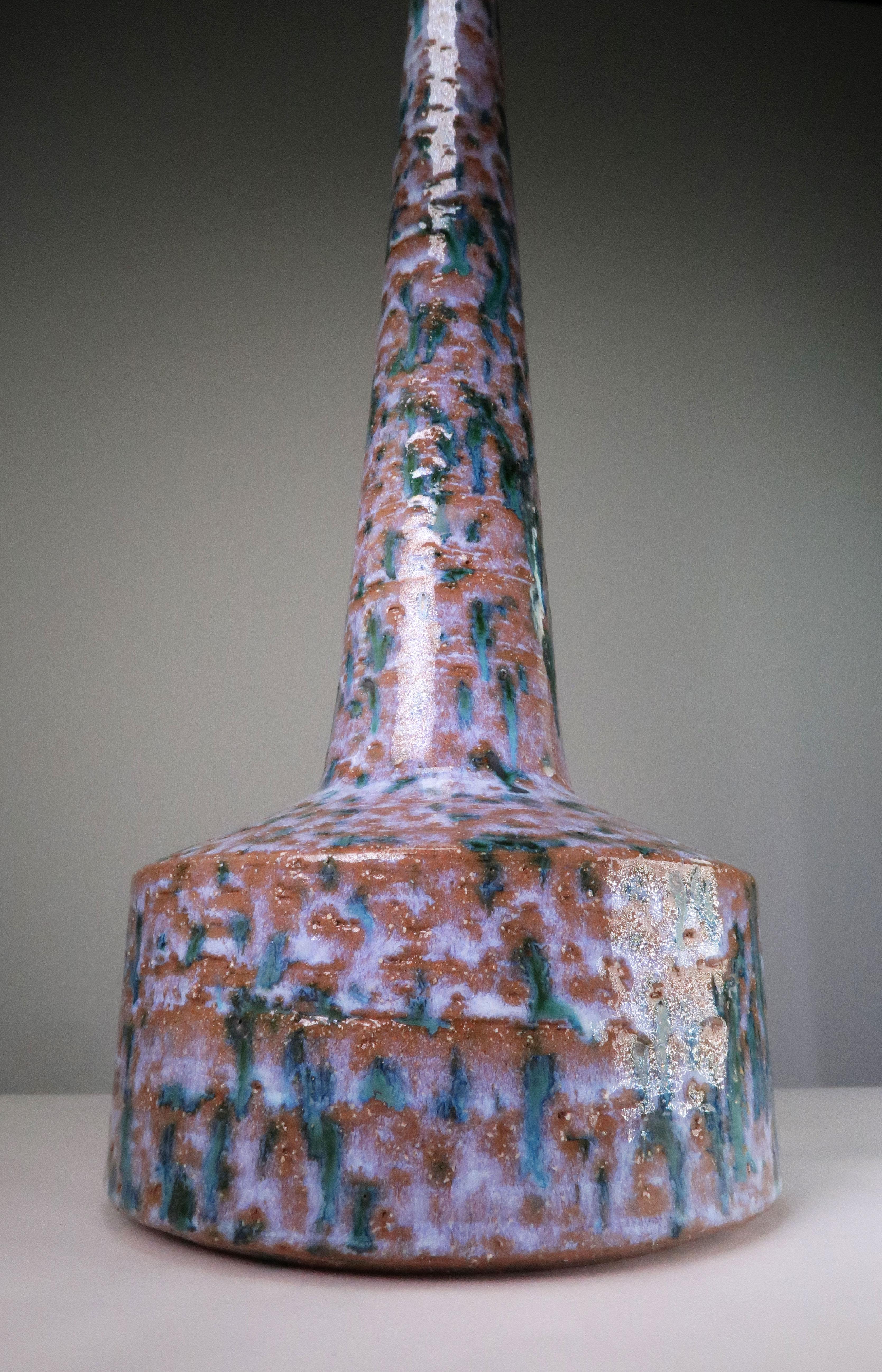 Tall and slender Danish Mid-Century Modern handmade and hand decorated ceramic table lamp with a extraordinary long neck. Rustic appearance with lilac, green, blue and black colors over warm brick colored clay that peeks through the multicolored