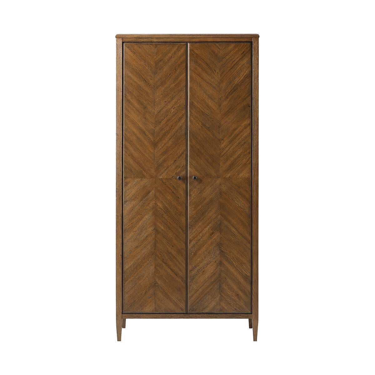 A modern rustic-style oak two-door cabinet with mirrored herringbone parquetry doors. It is adorned with elegant Verde Bronze knobs and rests upon tapered legs. 

Dimensions: 38