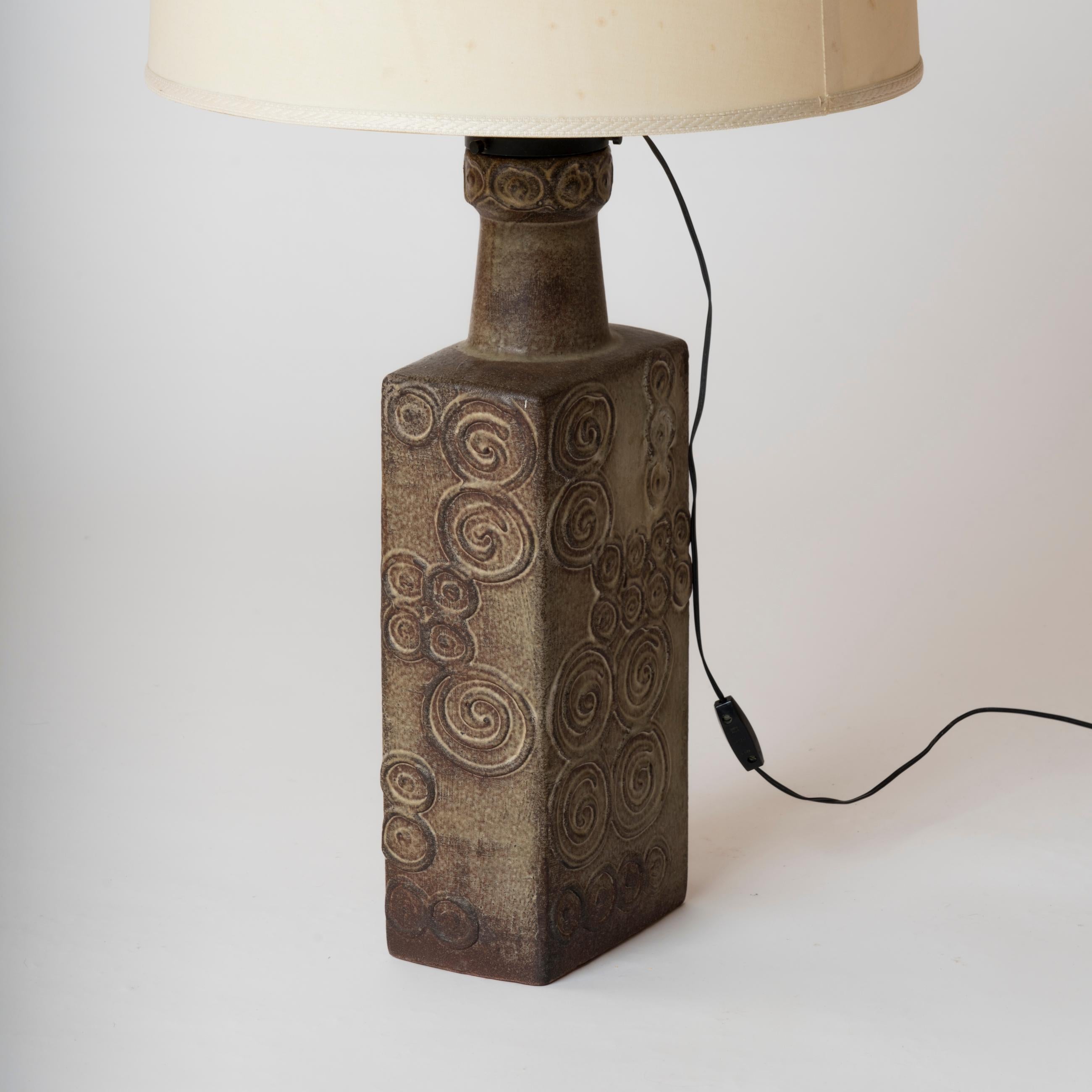 Tall rectangular terracotta lamp from the 1970s. Swirl-shaped patterns are reproduced on all sides of the lamp. The wiring is attached to the lampshade and requires rewiring.
European socket and wiring.
This lamp ships from France and can be