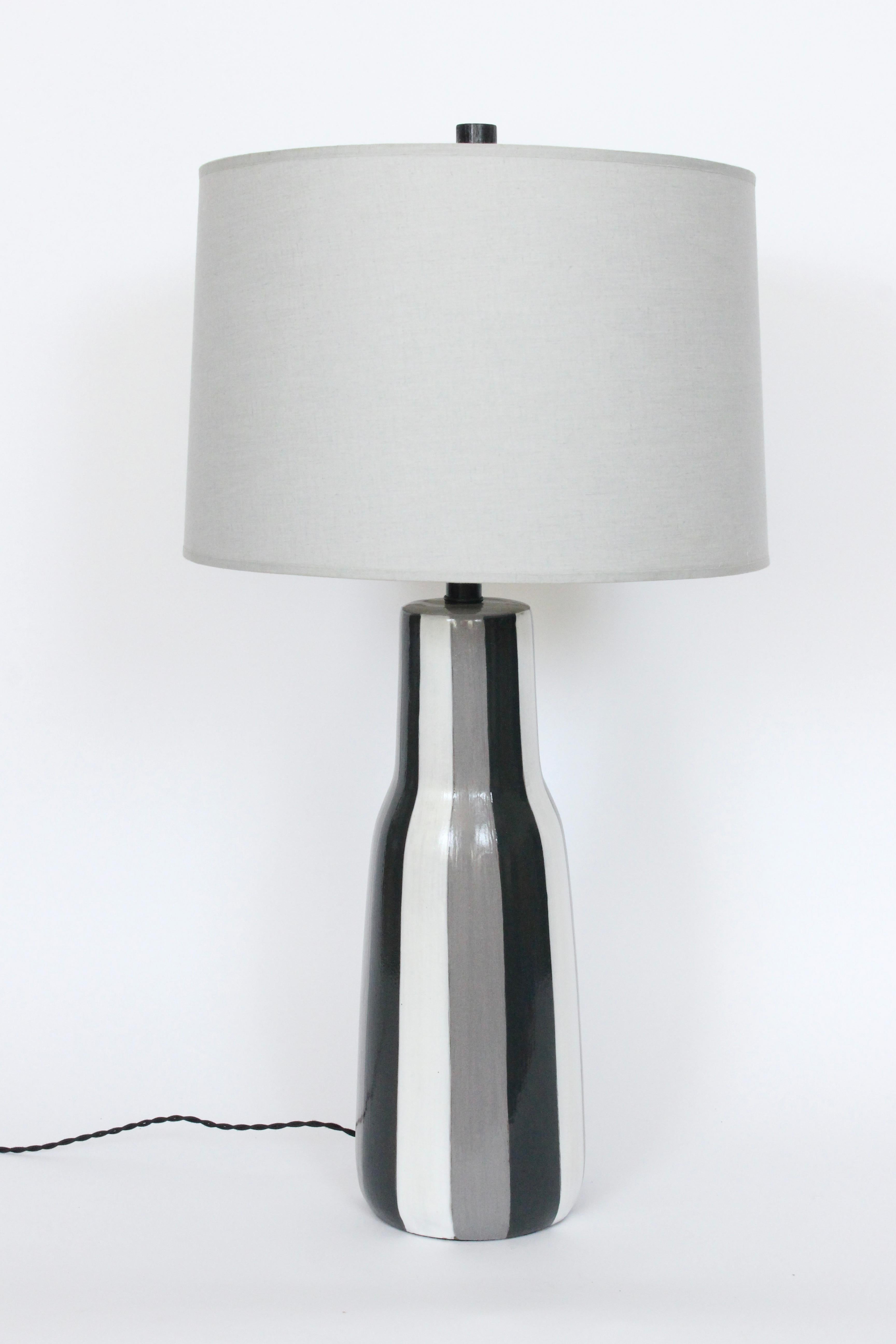 Monumental Design Technics handgefertigte glänzend glasierte Keramik Tischlampe. Geringe Stellfläche. Eine längliche Flaschenform mit handgemalten vertikalen Streifen in Grau, Schwarz und Weiß und einem originalen schwarz emaillierten Holzknauf. 