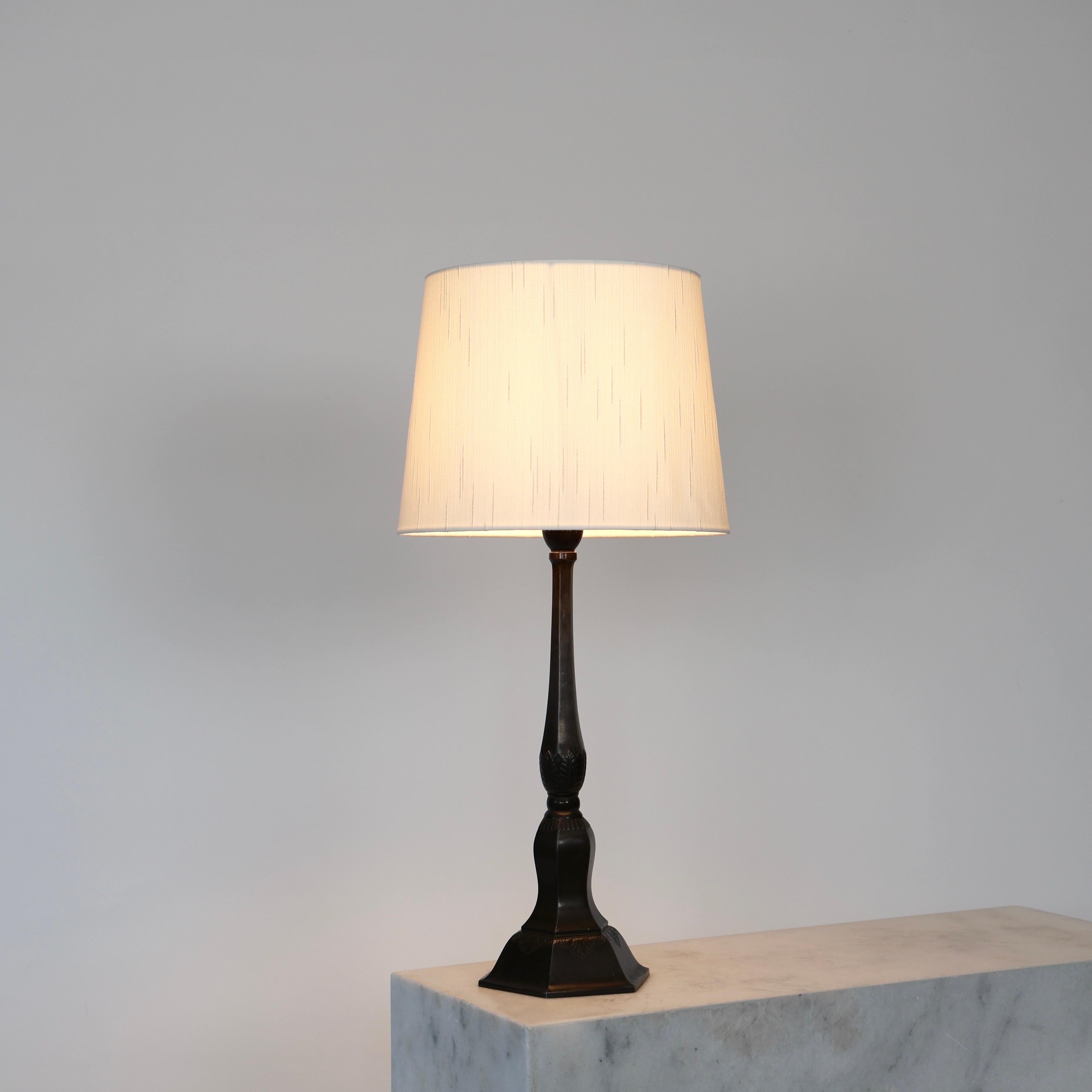 Early Just Andersen Diskometal Table Lamp made in 1926. A fine piece for an exquisite home.

* Tall diskometal table lamp on a 6-sided foot with ornaments and a white shade
* Designer: Just Andersen
* Model: D59
* Year: 1926-1929
* Condition: Fair