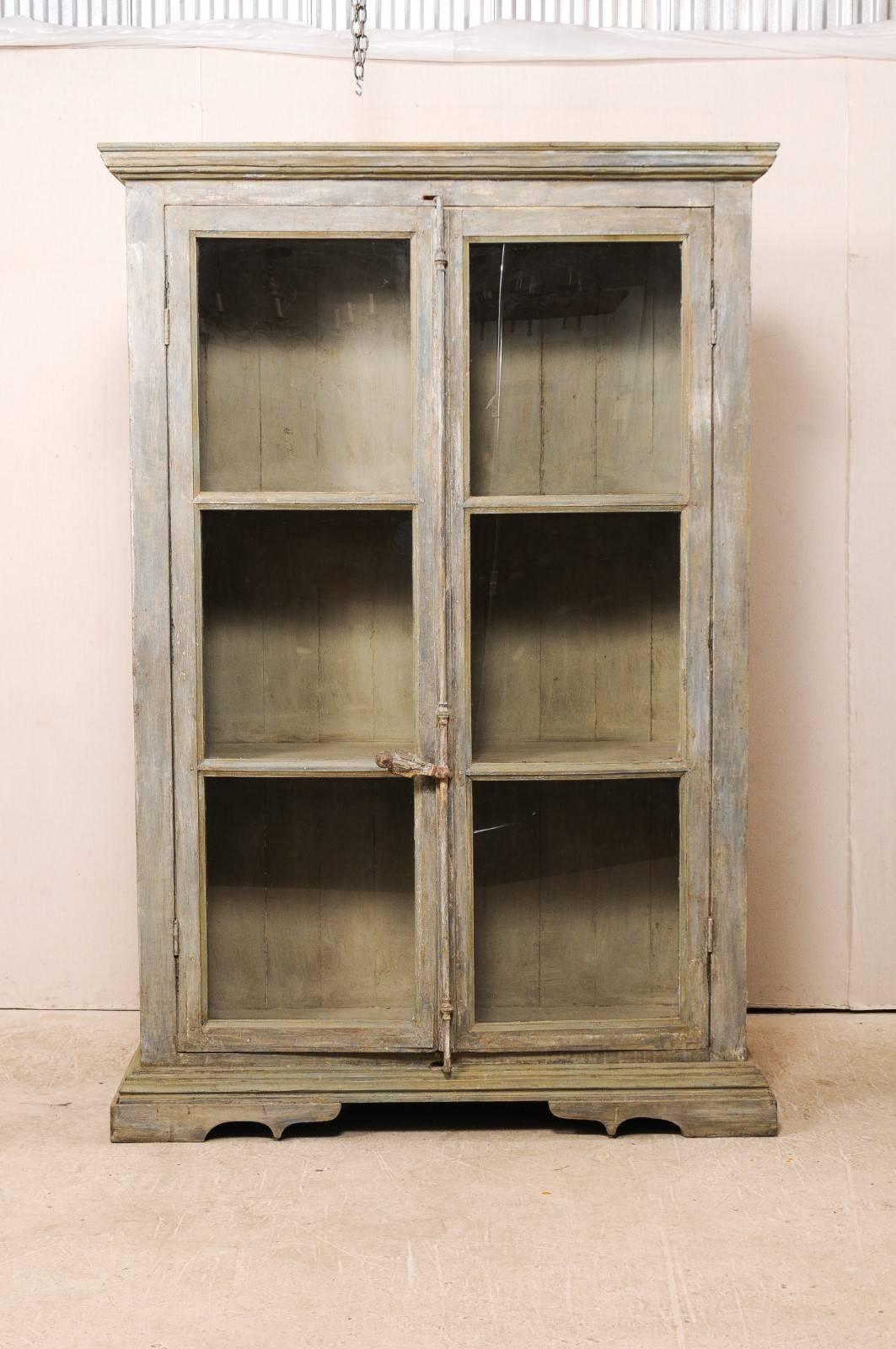 A tall display cabinet of 19th century French windows and reclaimed wood. This tall custom-made cabinet is comprised of two doors made from 19th century French windows, and a body of reclaimed and painted wood. This cabinet has substantial metal