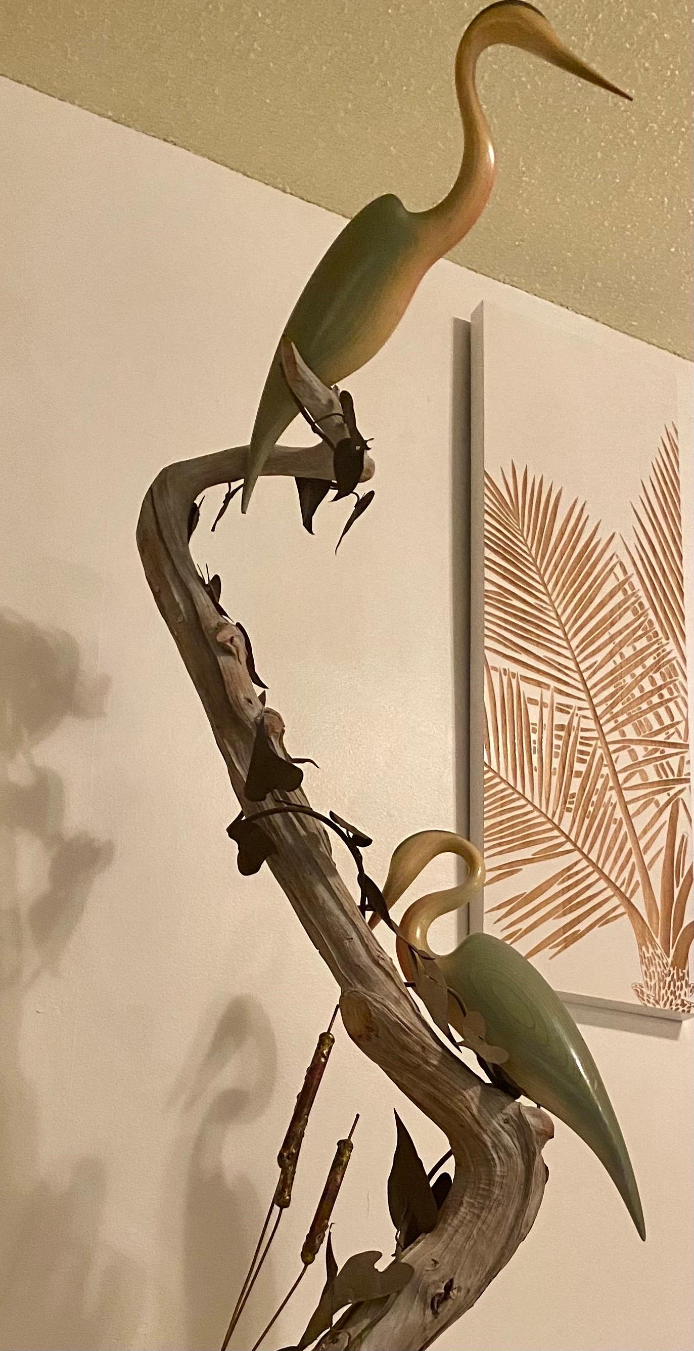 A unique and organic sculpture using driftwood intertwined with oxidized metal leaves and cattails. There are two hand carved birds perching on the wood. The sculpture is in wonderful condition and bring a beach vibe into any space.
