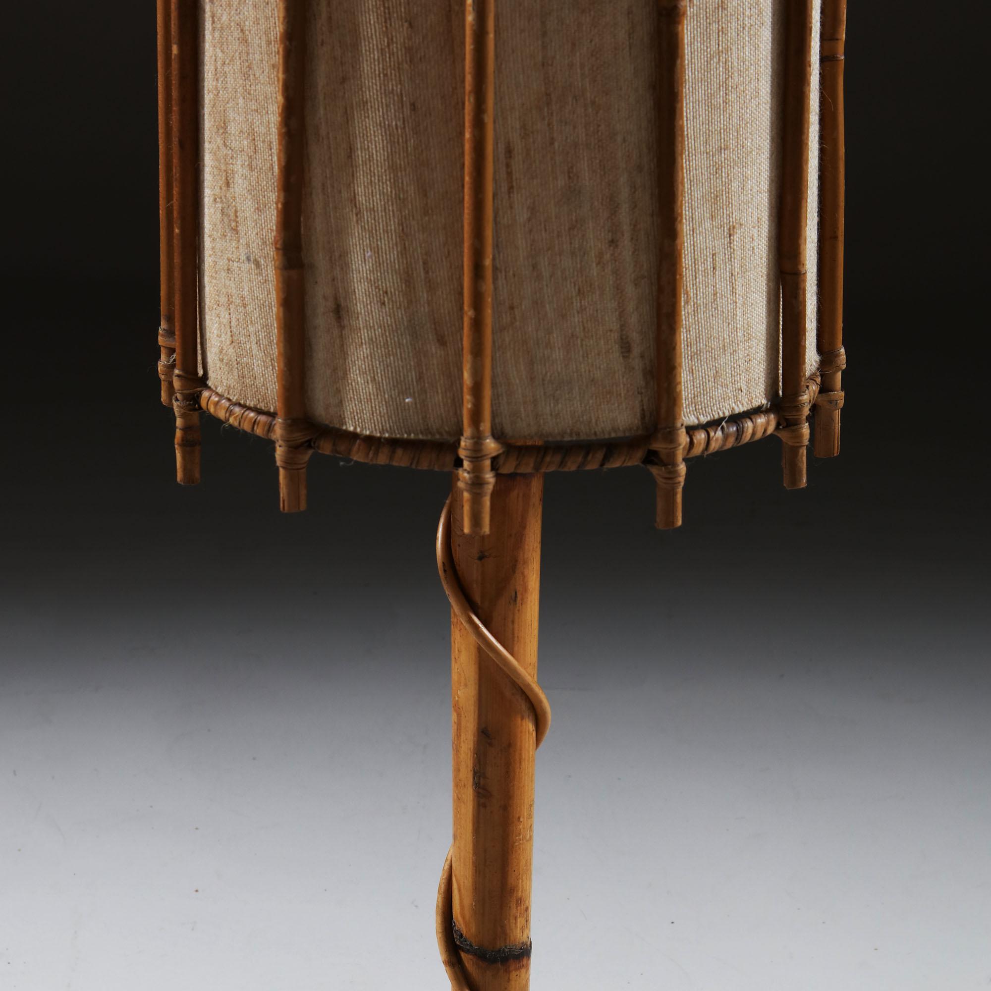 An unusual bamboo lamp, with spiral bamboo base, one strand climbing the central stem in imitation of a vine, surmounted by a tall conical shade.
