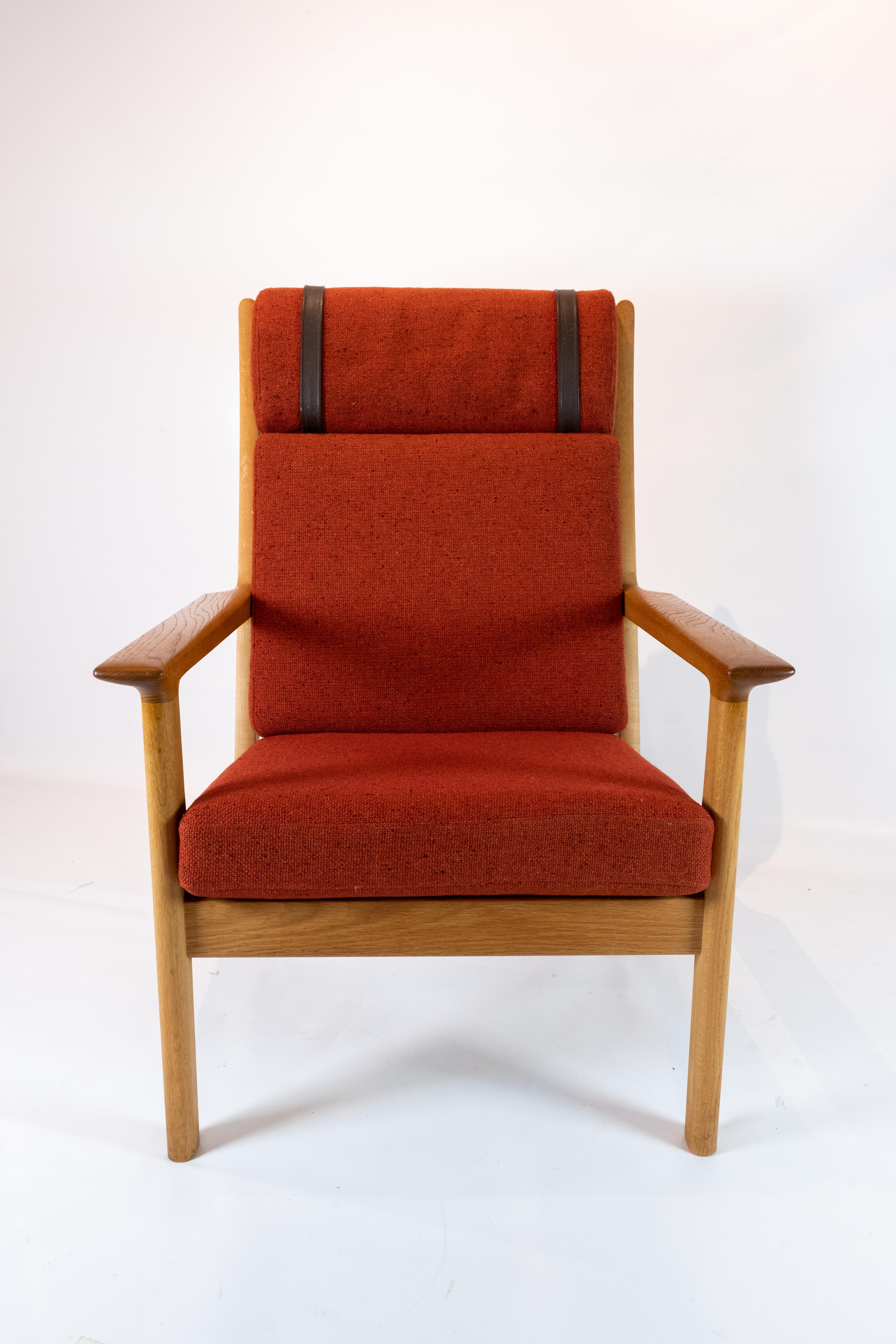 This tall easy chair, designed by the renowned Hans J. Wegner and meticulously crafted by GETAMA in the 1960s, epitomizes the elegance and comfort of Scandinavian design. Crafted from solid oak and upholstered in vibrant red wool fabric, it exudes