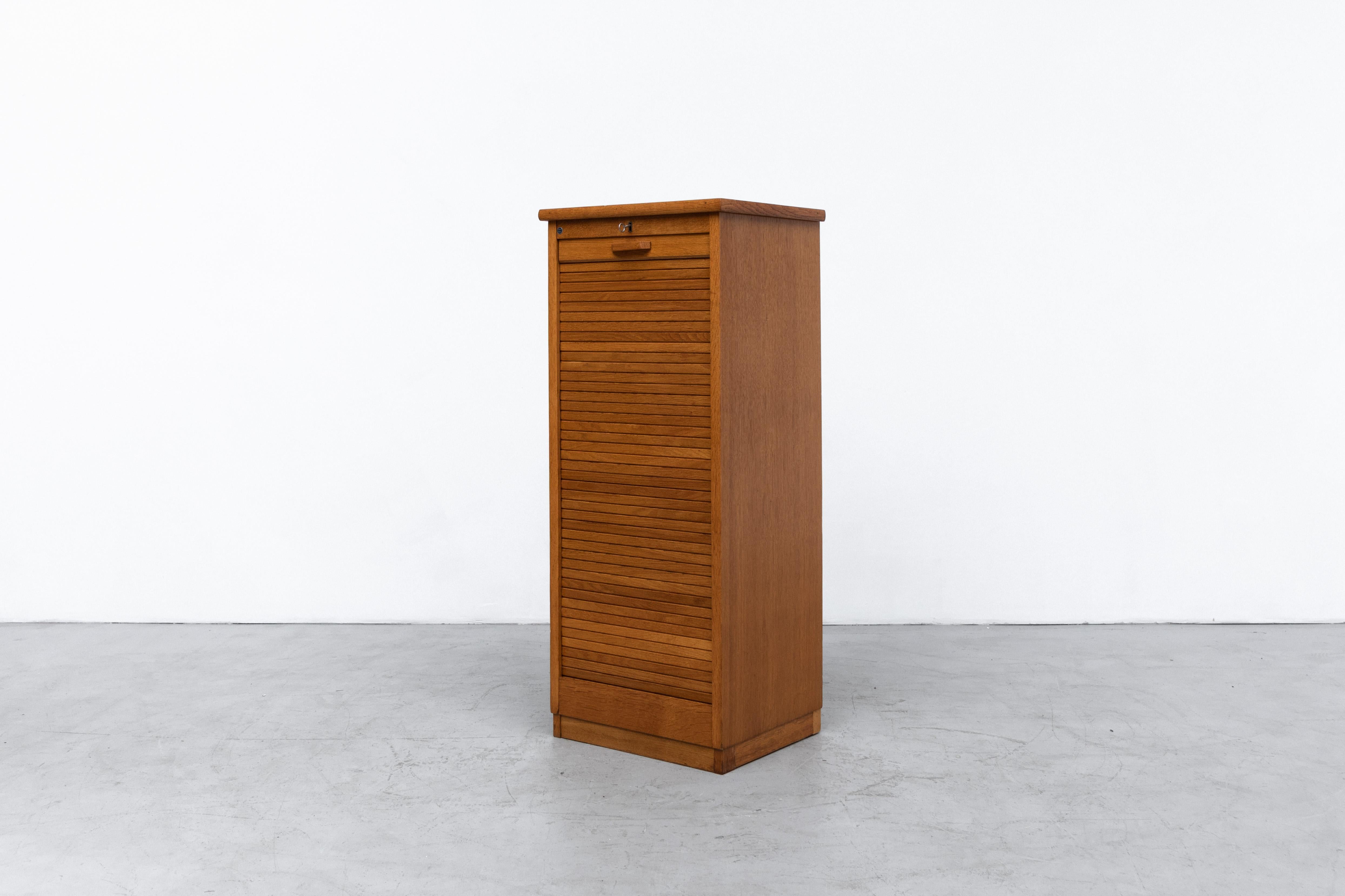 Tall Eeka file cabinet with stacked birch drawers and magazine storage rack behind locking tambour door. In original condition with key, visible wear and some (non active) wormwood holes. Similar Eeka cabinets also available listed separately.
