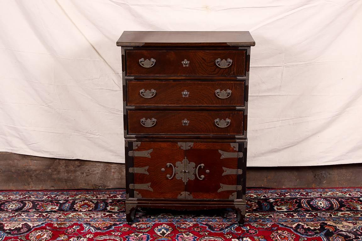Tall exotic wood tansu chest, lacquered wood chest with three drawers with brass bat wing hardware over a two-door cabinet with decorative hardware and pulls (the lock lacking the closure pin), inside lined with lacquered character printed papers,