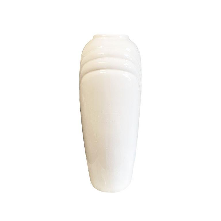Tall white 1980s style ceramic vase in creamy white color with wonderful proportions. The body of this vase is oval in shape, with a small round base which widens through the middle, and tapers at the top. The body is decorated with an overlapping