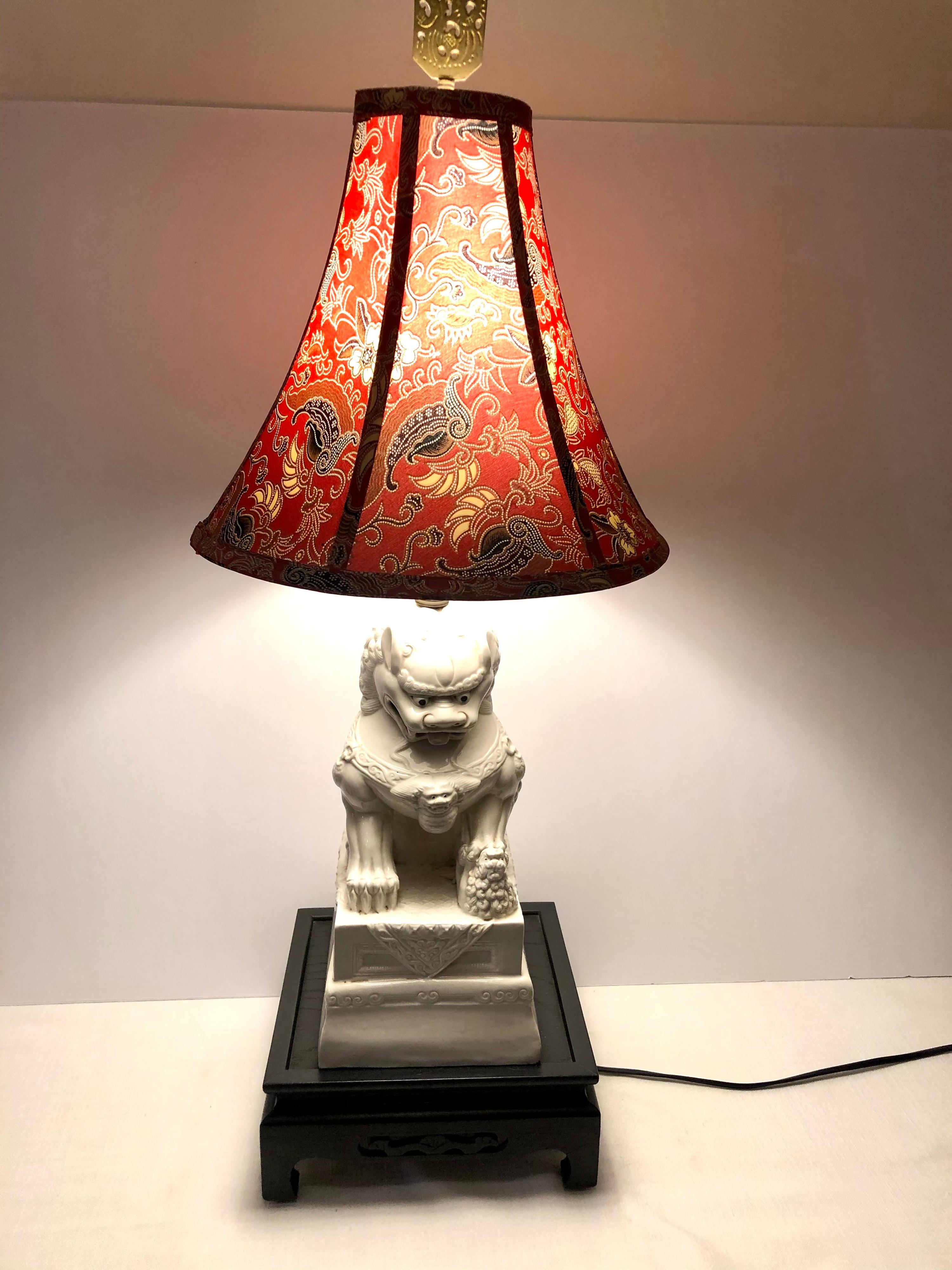 I want the offer you this wonderful tall foo dog lamp with this beautiful red lamp shade. He is a totally charming foo dog. I love the expression on his face. He is holding a baby foo dog under his right paw. The intricate design on this red lamp