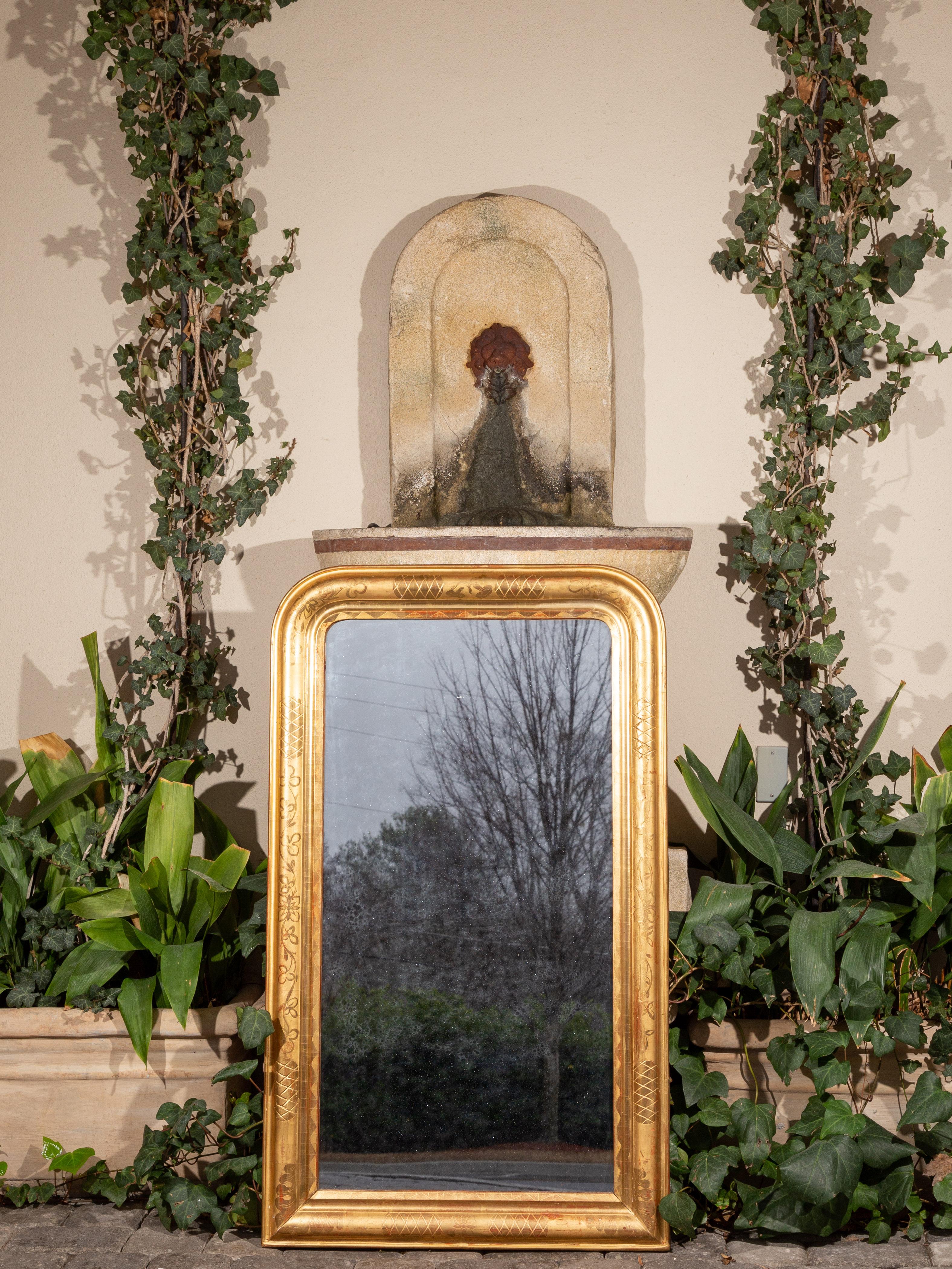 A large French giltwood Louis-Philippe style mirror from the early 20th century, with clover and crosshatch motifs. Created in France during the early years of the 20th century, this tall gilded mirror features the traditional Louis-Philippe