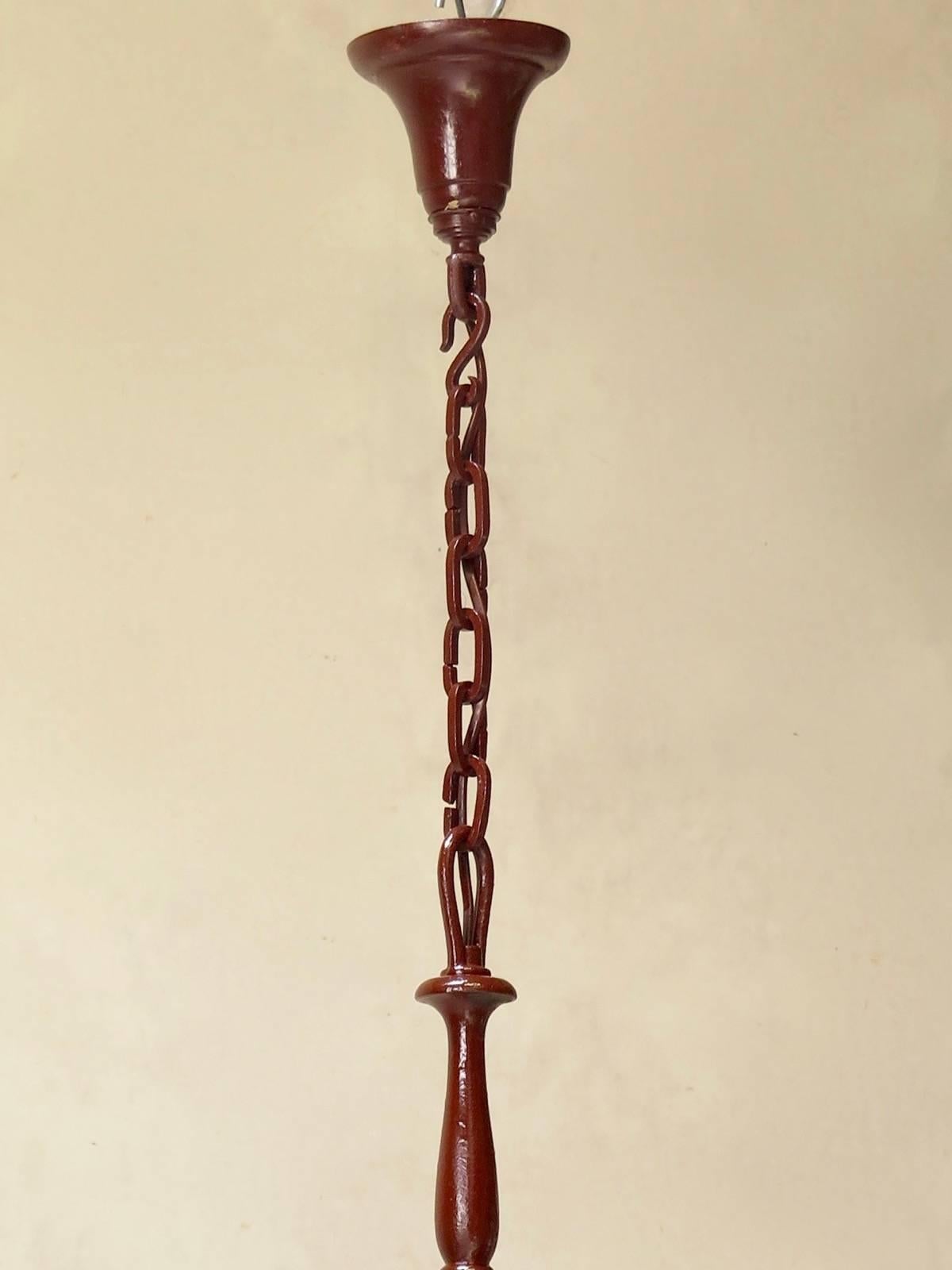 Very long, elegant, turned wrought-iron eight-arm chandelier, painted a deep red color.