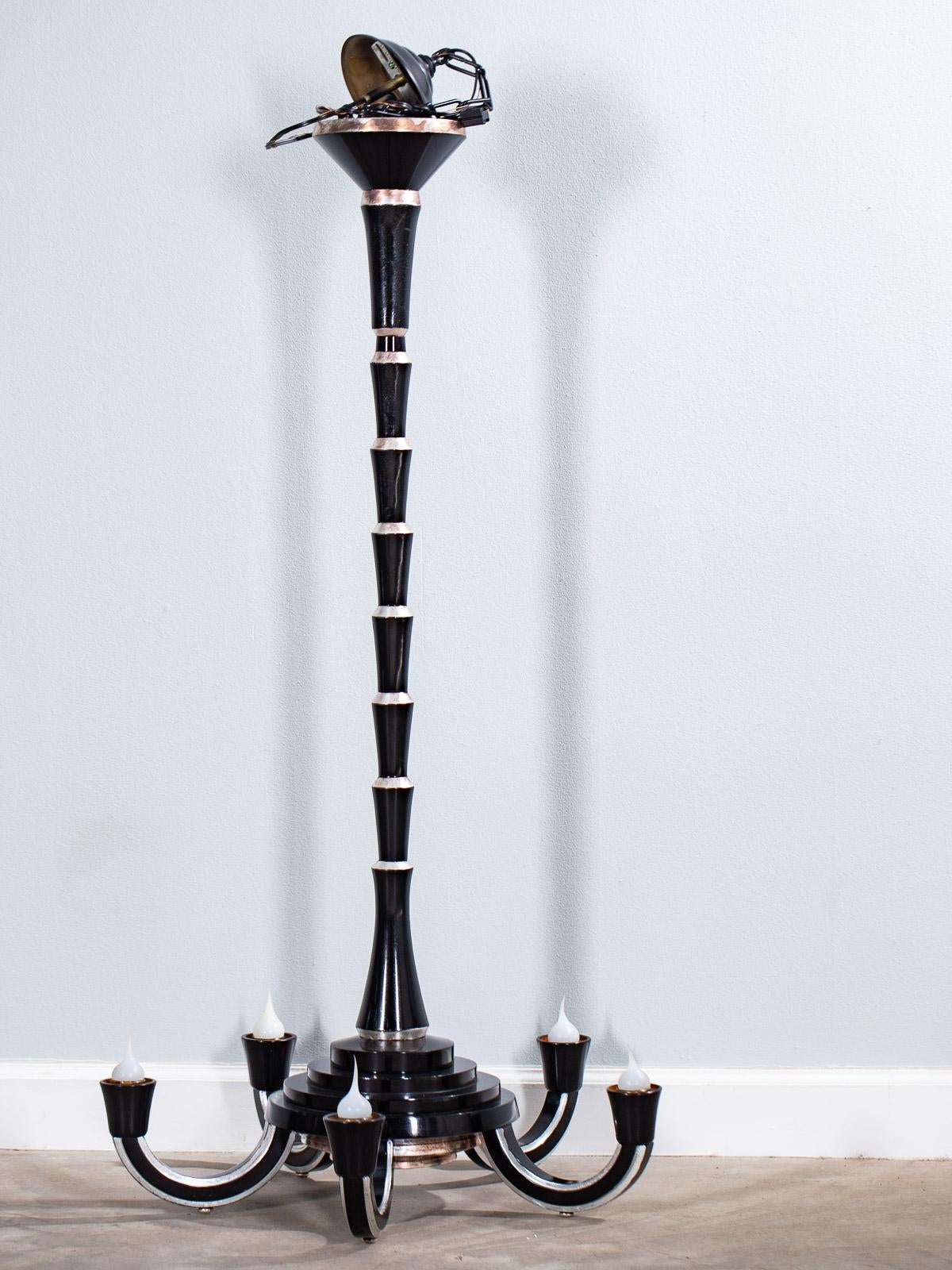 A chic French Art Deco ebonized and silver leaf timber five-arm chandelier circa 1930 of exceptional height. The iconic shape of this French light fixture embodies the architectural underpinnings of the Art Deco period. The tall column consists of a