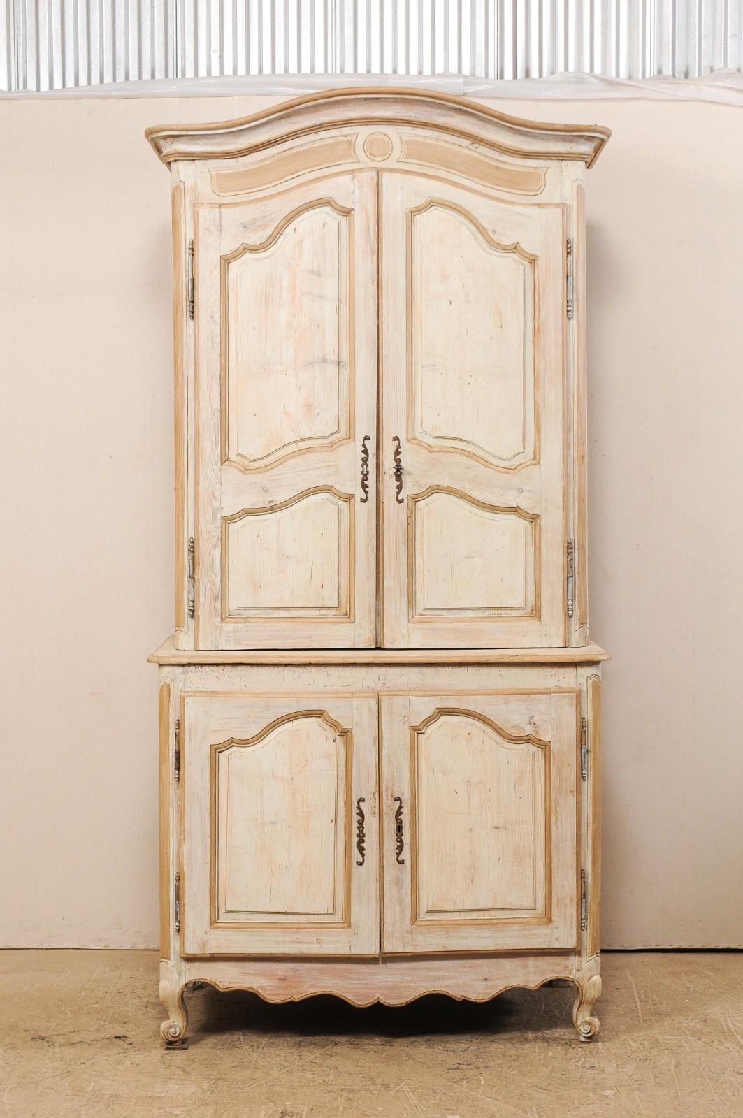 A tall French painted wood storage cabinet from the turn of the 18th and 19th century. This tall French antique cabinet features a delicately arched and molded center top pediment, carved, rounded side posts, a scalloped skirt along three sides, and