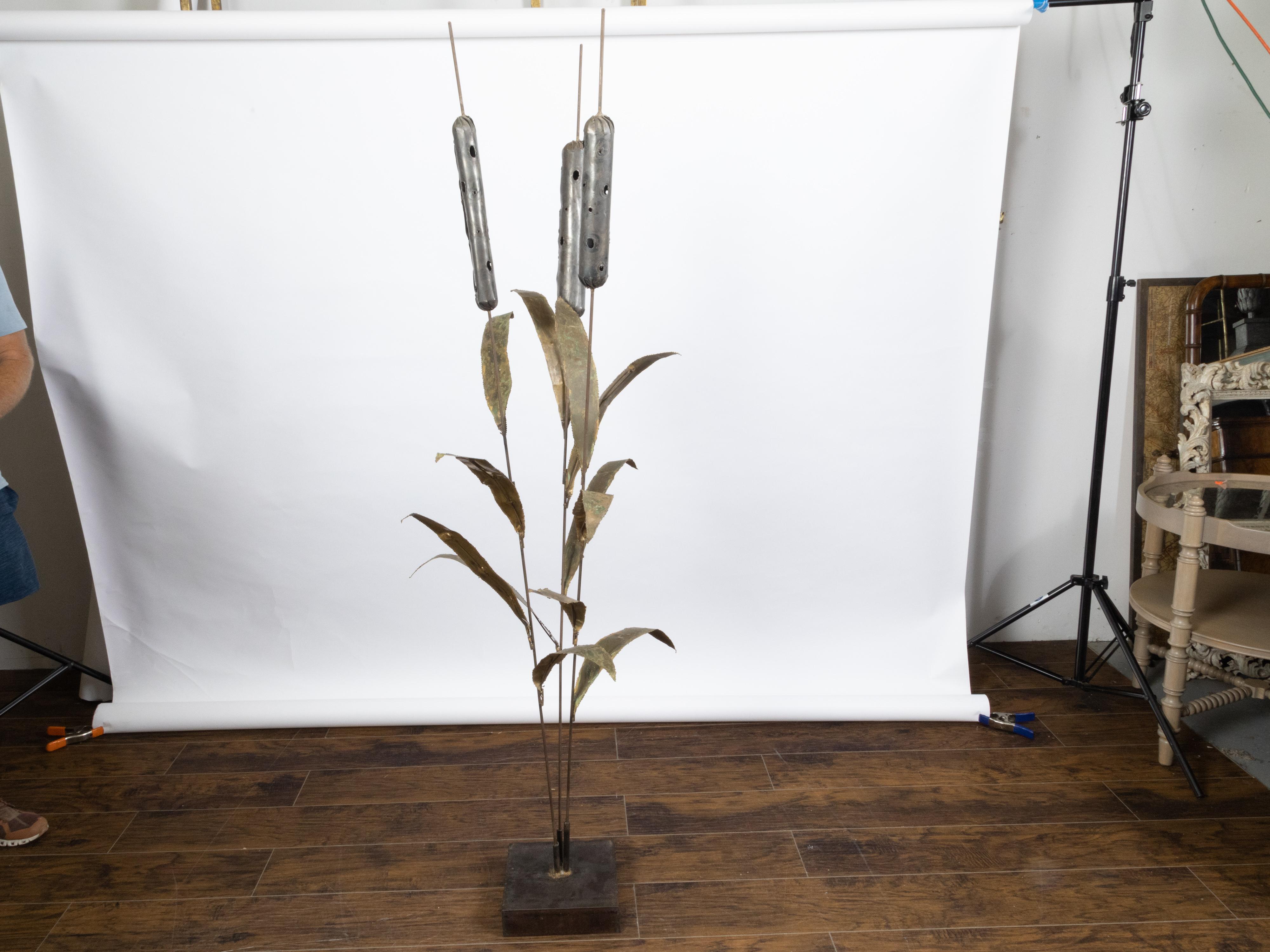 A large French metal cattail sculpture from the mid 20th century, with square base. Created in France during the midcentury period, this tall cattail foliage sculpture attracts our attention with its rustic appearance and weathered patina. Mounted