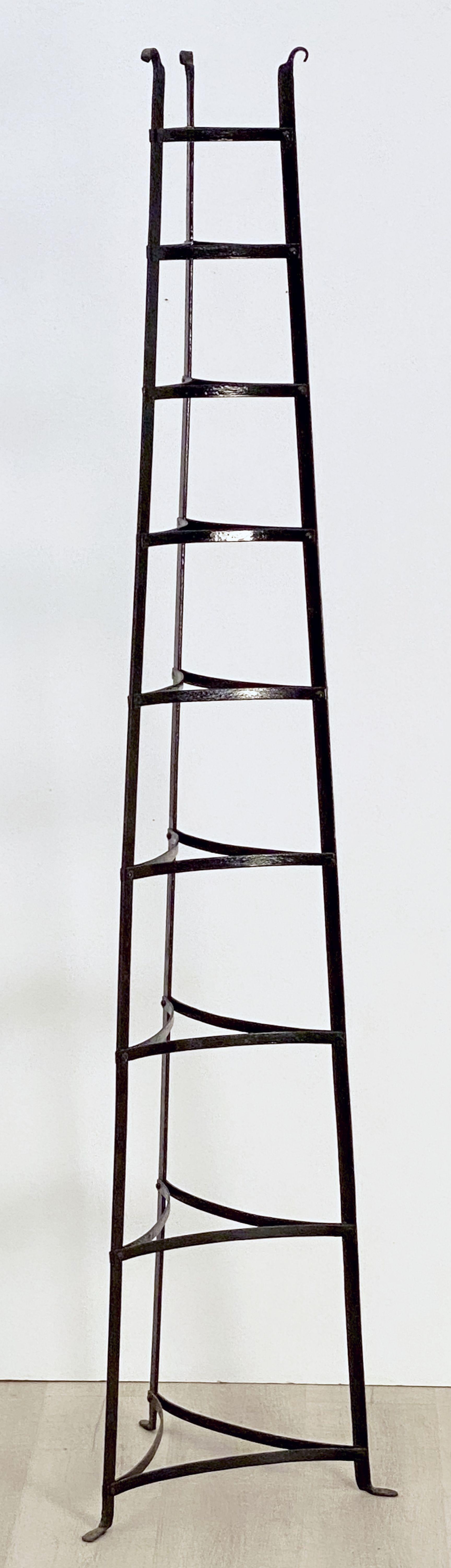A fine French pan or pot stand of wrought iron featuring nine triangular fitted tiers on a tripod support for the display of cookware.

Can be used for garden pots and other decorative uses as well.
