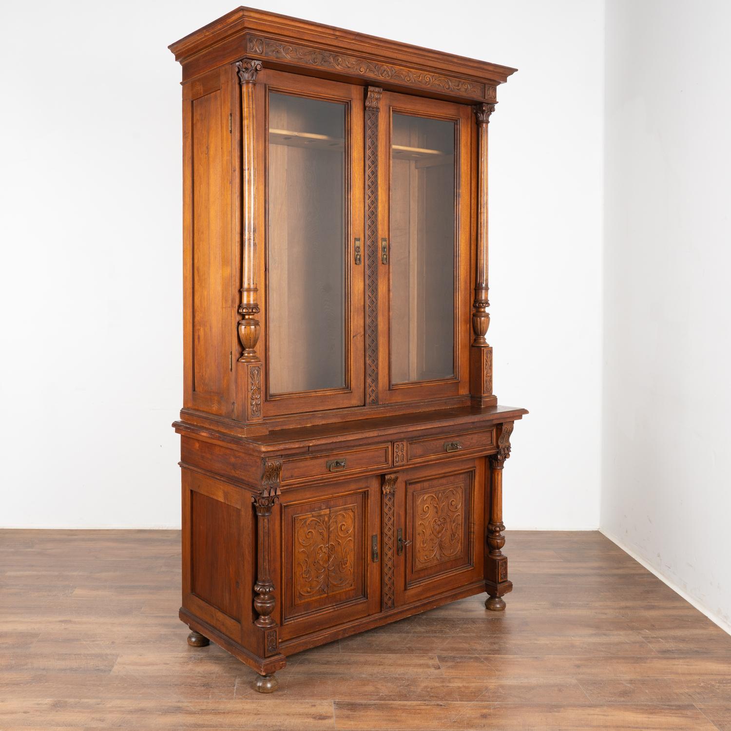 Striking walnut gun cabinet with attractive carving and turned columns. Holds 9 guns and stands over 8' tall.
Lower cabinet has two drawers over two doors with interior shelf.
Locks currently function with 2 keys included.
Built in two sections for