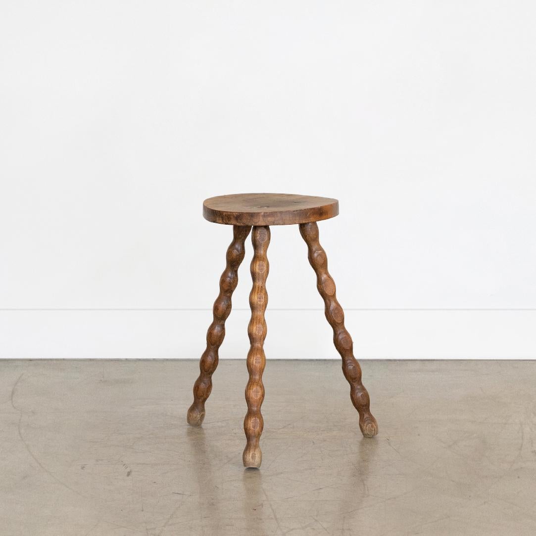 Tall vintage wood stool with beautiful wavy wood legs from France. Circular seat with original wood finish showing great age markings and patina. Can be used as small stool or as side table next to chairs. 



