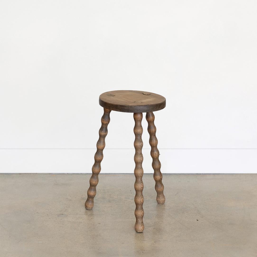 Tall vintage wood stool with beautiful wavy wood legs from France. Circular seat with original wood finish showing great age markings and patina. Can be used as small stool or as side table next to chairs. 

Seat measures 10