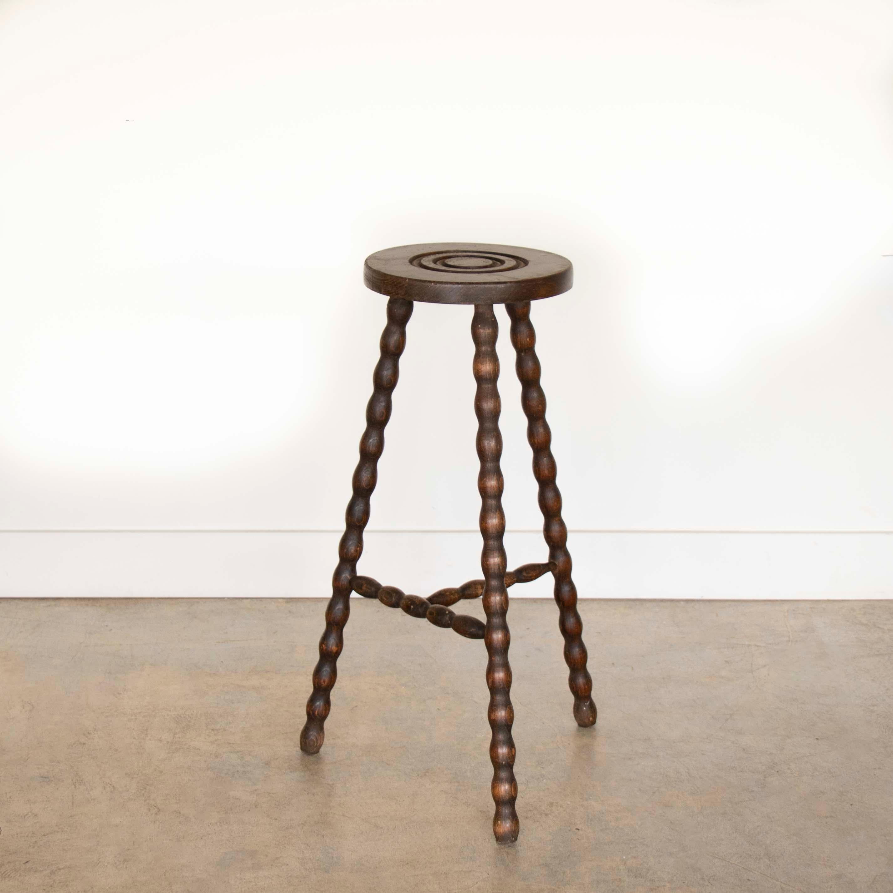 Vintage Holzhocker mit schönen gewellten Holzbeinen aus Frankreich. Runde Sitzfläche mit einzigartigem, geschnitztem Ringdetail auf der Oberseite. Originale Holzoberfläche mit tollen Altersspuren und Patina. Kann als Hocker oder als Beistelltisch