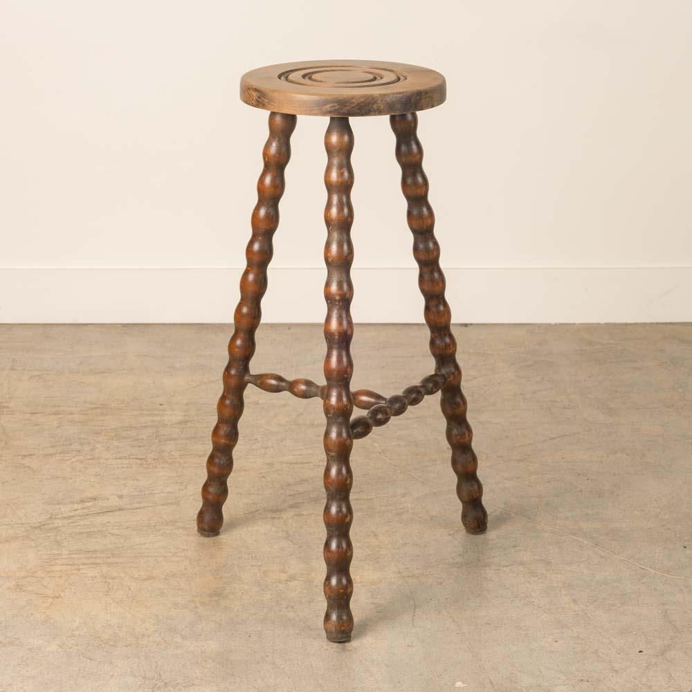 Vintage Holzhocker mit schönen gewellten Holzbeinen aus Frankreich. Runde Sitzfläche mit einzigartigem, geschnitztem Ringdetail auf der Oberseite. Originale Holzoberfläche mit tollen Altersspuren und Patina. Kann als Hocker oder als Beistelltisch