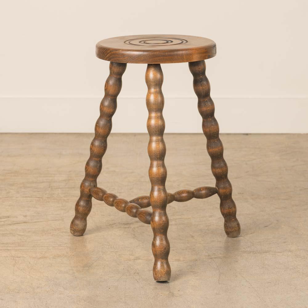 Vintage Holzhocker mit schönen gewellten Holzbeinen aus Frankreich. Runde Sitzfläche mit einzigartigem, geschnitztem Ringdetail auf der Oberseite. Originale Holzoberfläche mit schönen Altersspuren und Patina. Kann als Hocker oder als Beistelltisch