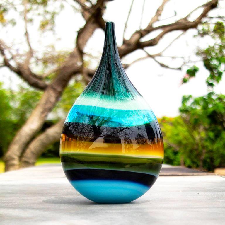 This hand blown glass vase draws inspiration from the rich hues and undulating topography of Southern California. Alternating layers of opaque and transparent colors are applied to clear glass to create a Scandinavian Modern style. Overlaps create